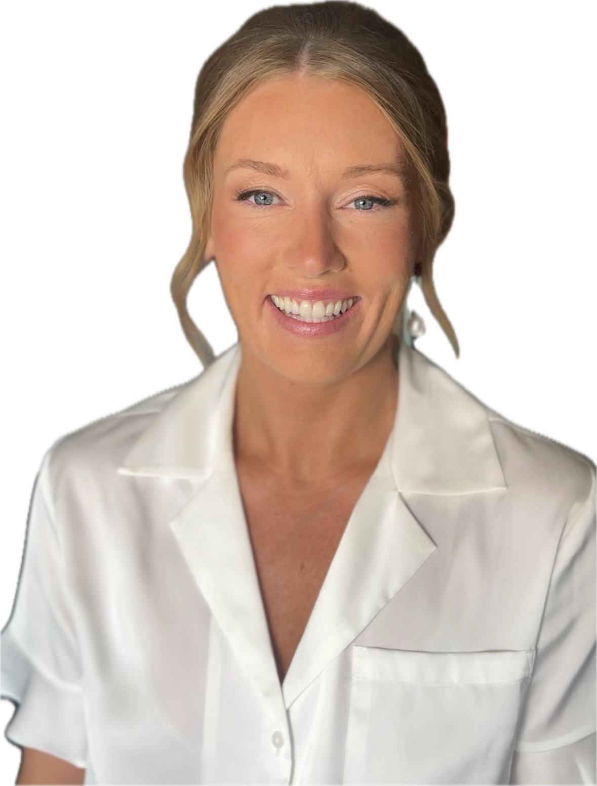 A smiling woman with blonde hair styled in loose waves, wearing a white collared shirt, and pearl earrings in front of a plain background.