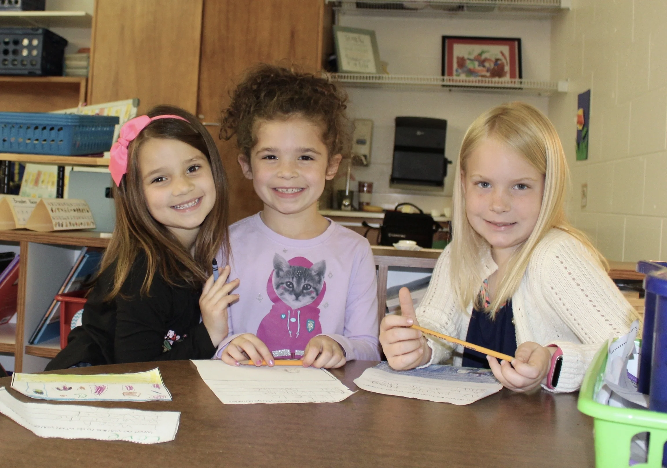 Three smiley girls working at desk