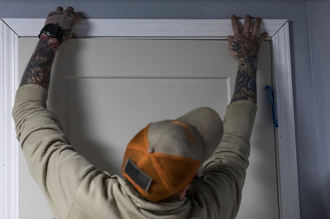 Patterson lines up the newly cut trim above a door in his house.