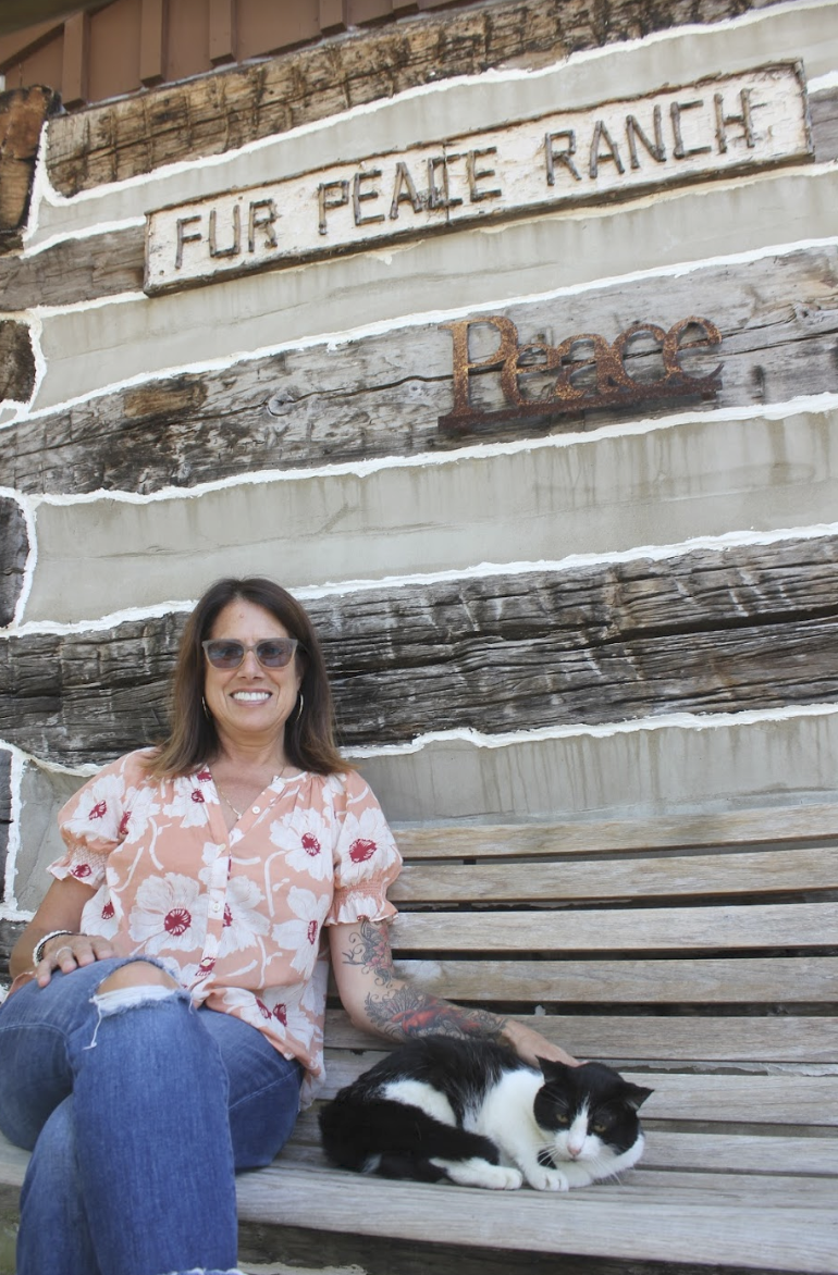 Vanessa and her cat, Zamir, sitting on one of the porches at Fur Peace Ranch.