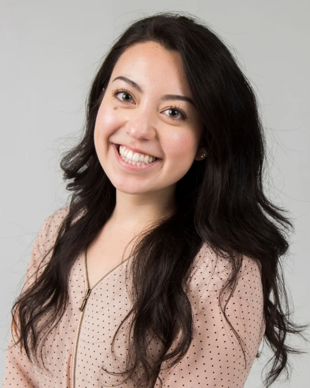 Woman smiling, wearing pale pink sweater.