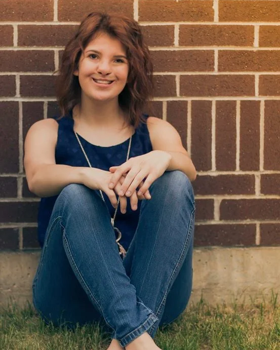Woman sitting down with her legs crossed, smiling.
