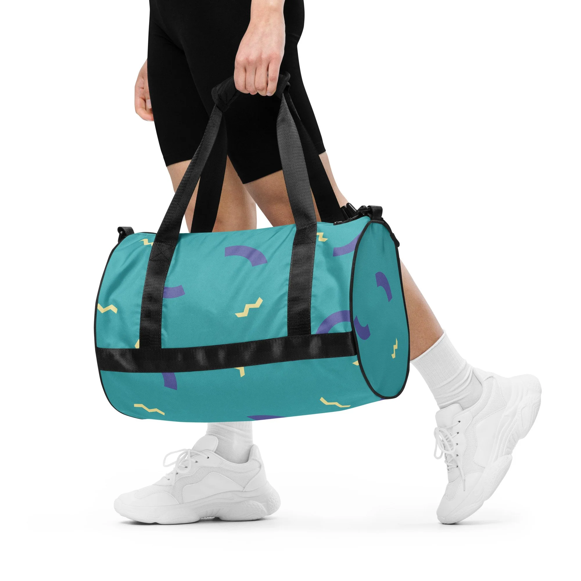 photo of a person from the waist down, holding a colorful blue and purple duffel bag