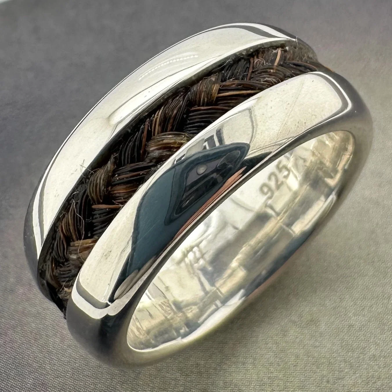 Close-up of sterling silver 10mm horsehair ring showing braided inlay detail and .925 hallmark.