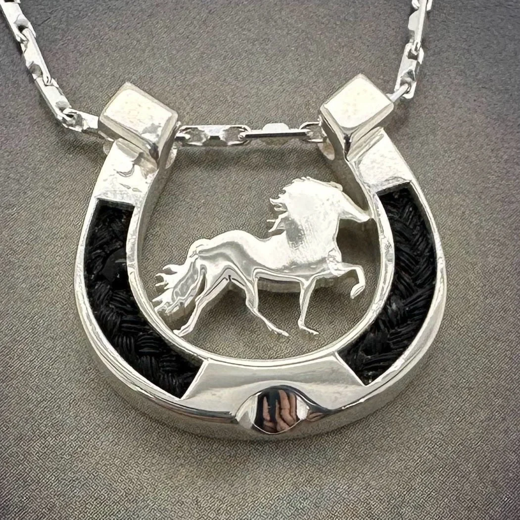 Sterling silver horseshoe pendant with inlaid horsehair and an Icelandic horse silhouette in the center.