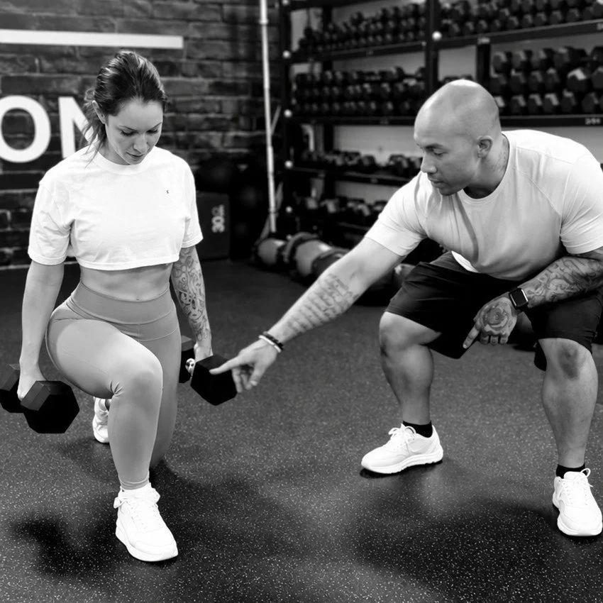 Dre coaching a client through a dumbbell lunge at Inner G Fitness