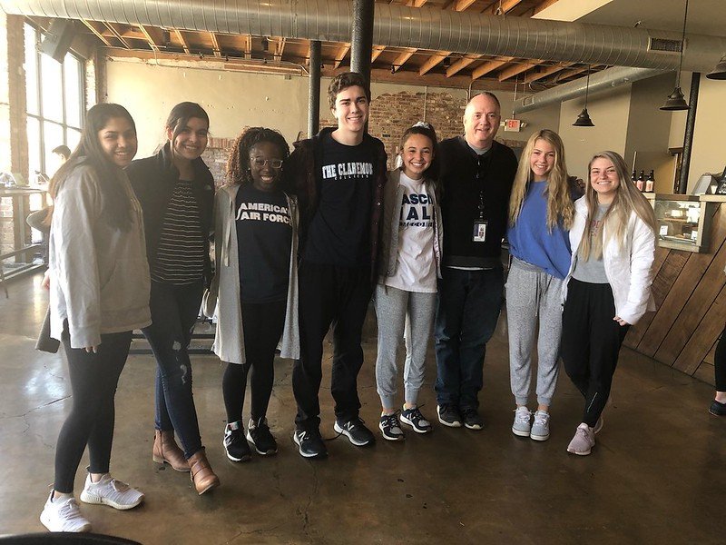 Mike Brose stands with student group at coffee shop