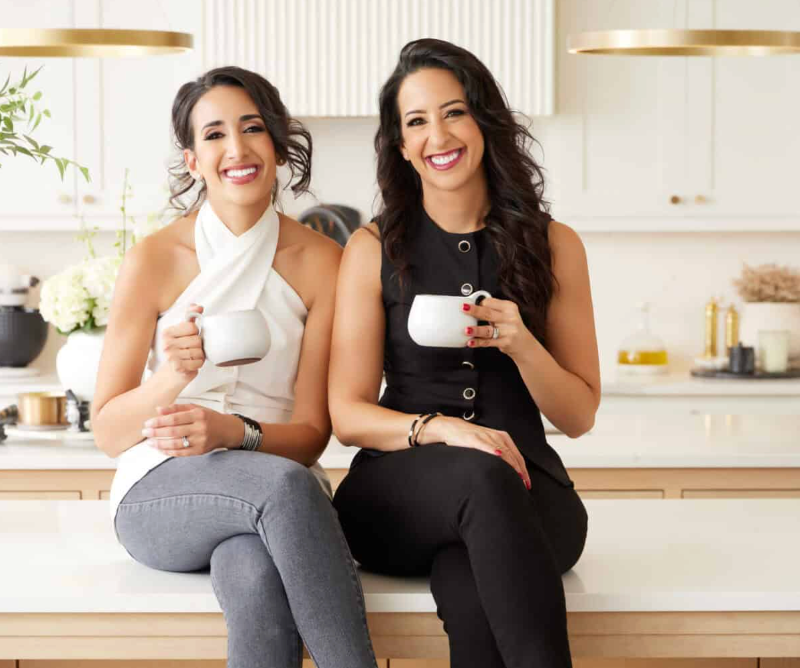 Alia and Radwa (Food Dolls) sitting on a counter holding mugs.