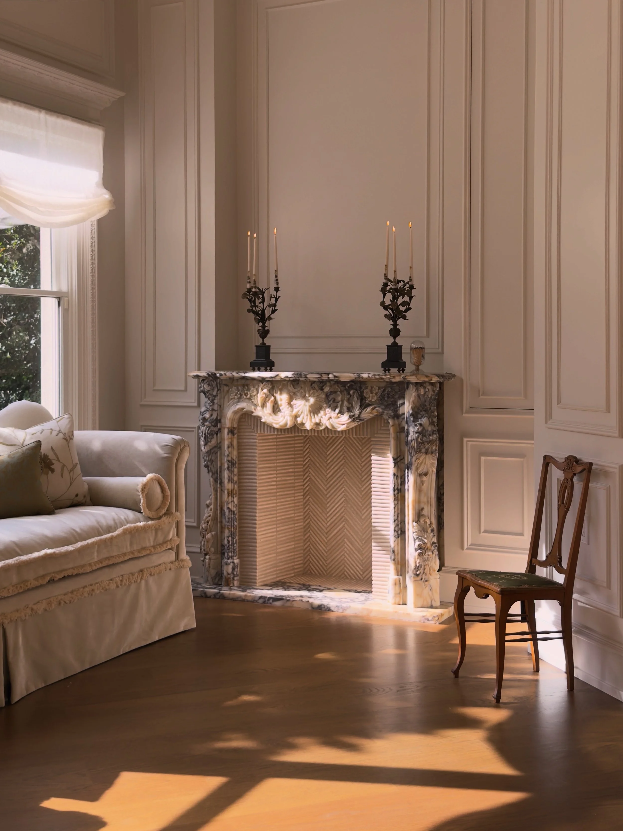 CIËN Interiors – hand carved viola marble fireplace with herringbone limestone tile fire box and French panel walls