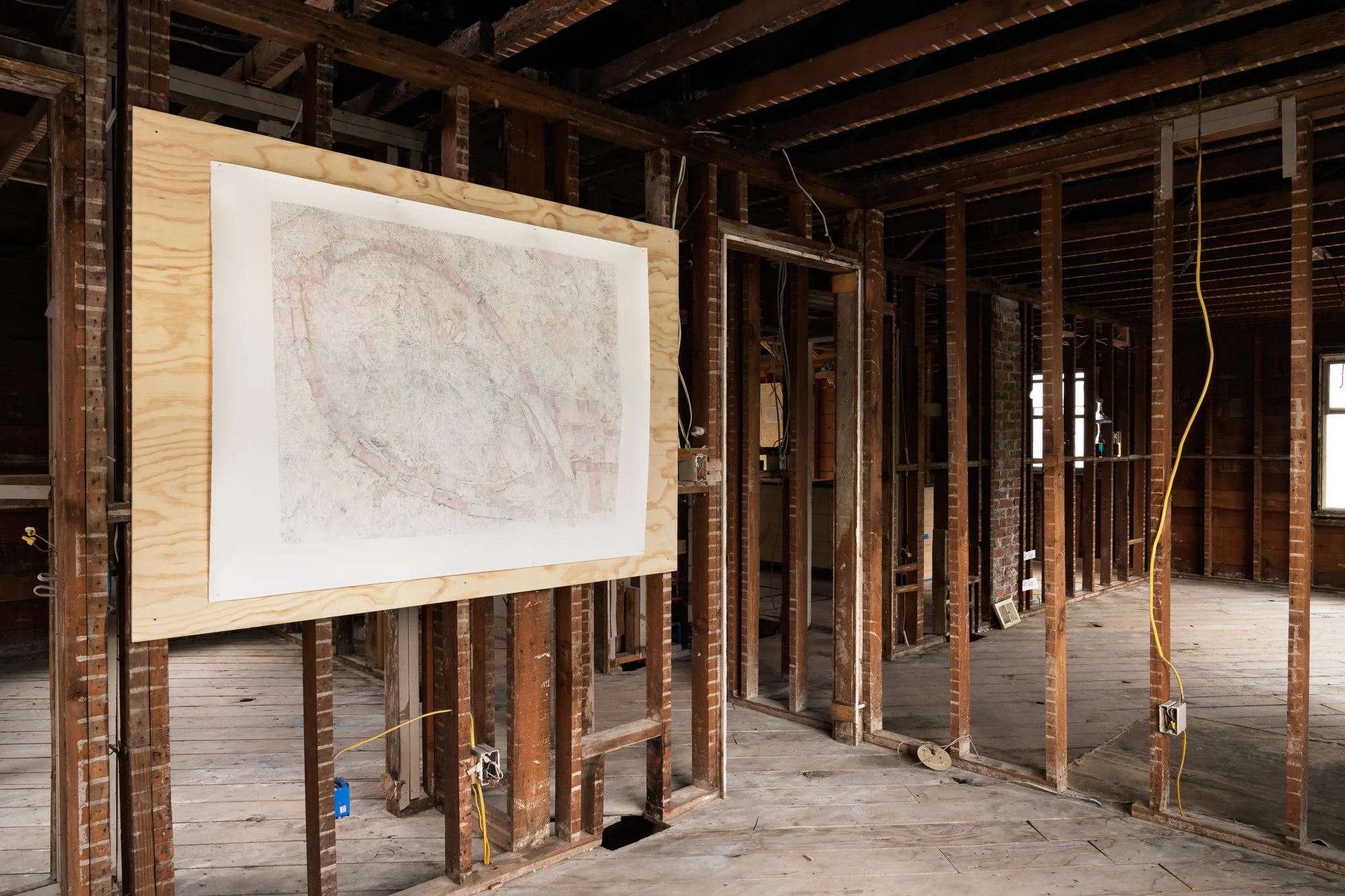 a large drawing on a piece of plywood attached to bare studs