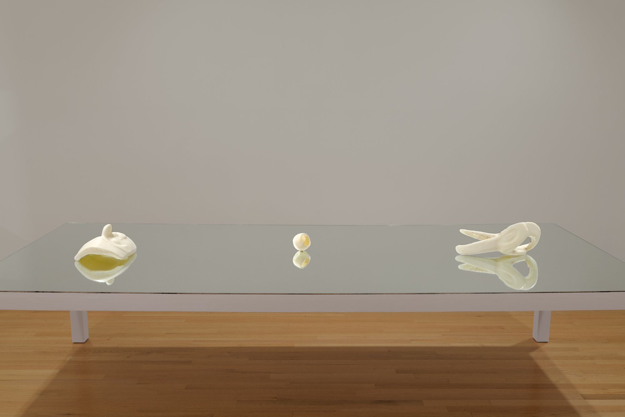three 3D printed sculptures on a table with a mirror top