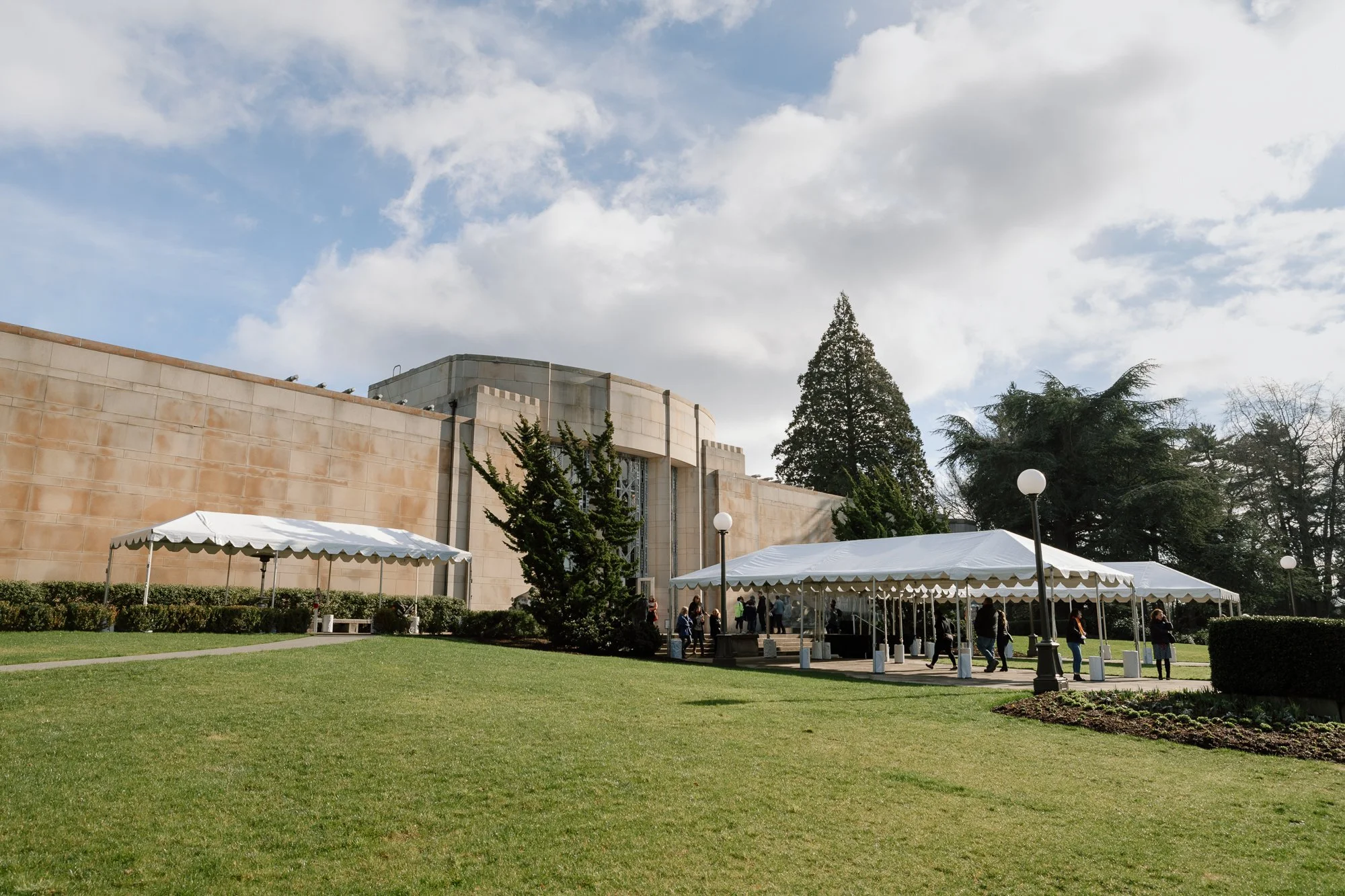 a large stone building with green lawn and white tents in front