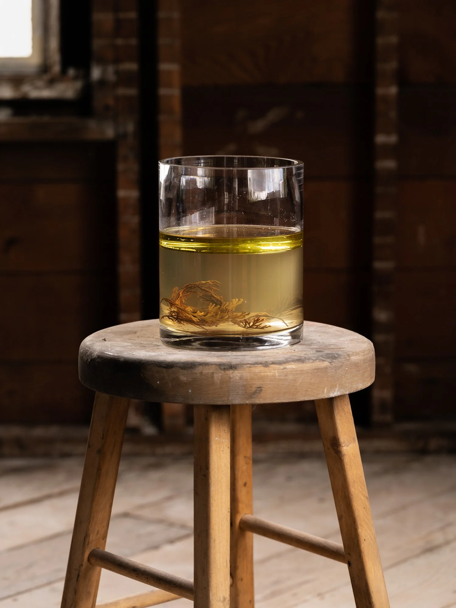 a glass vessel with yellow liquid sits on a stool