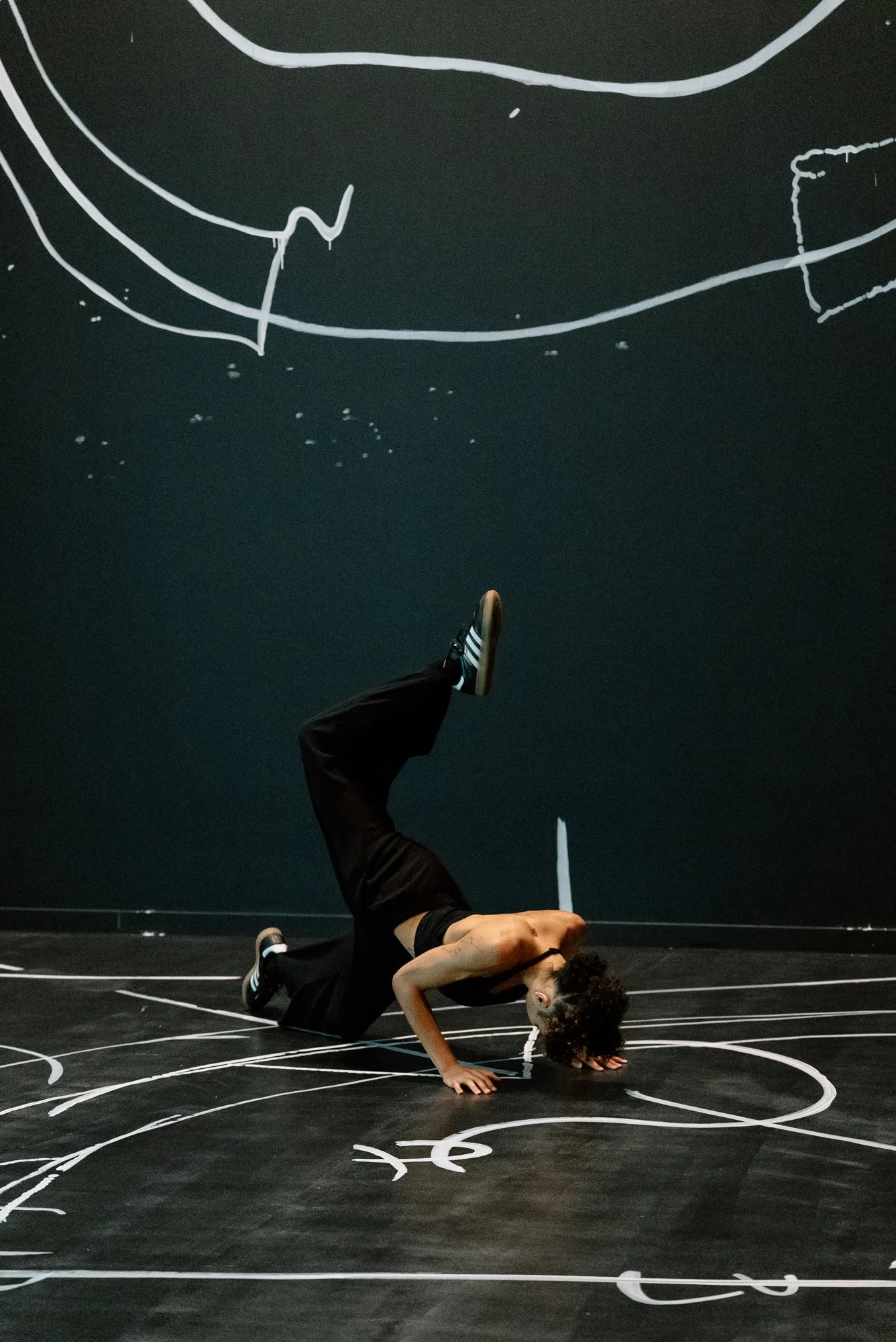 a dancer performing in a room painted black with white drawings