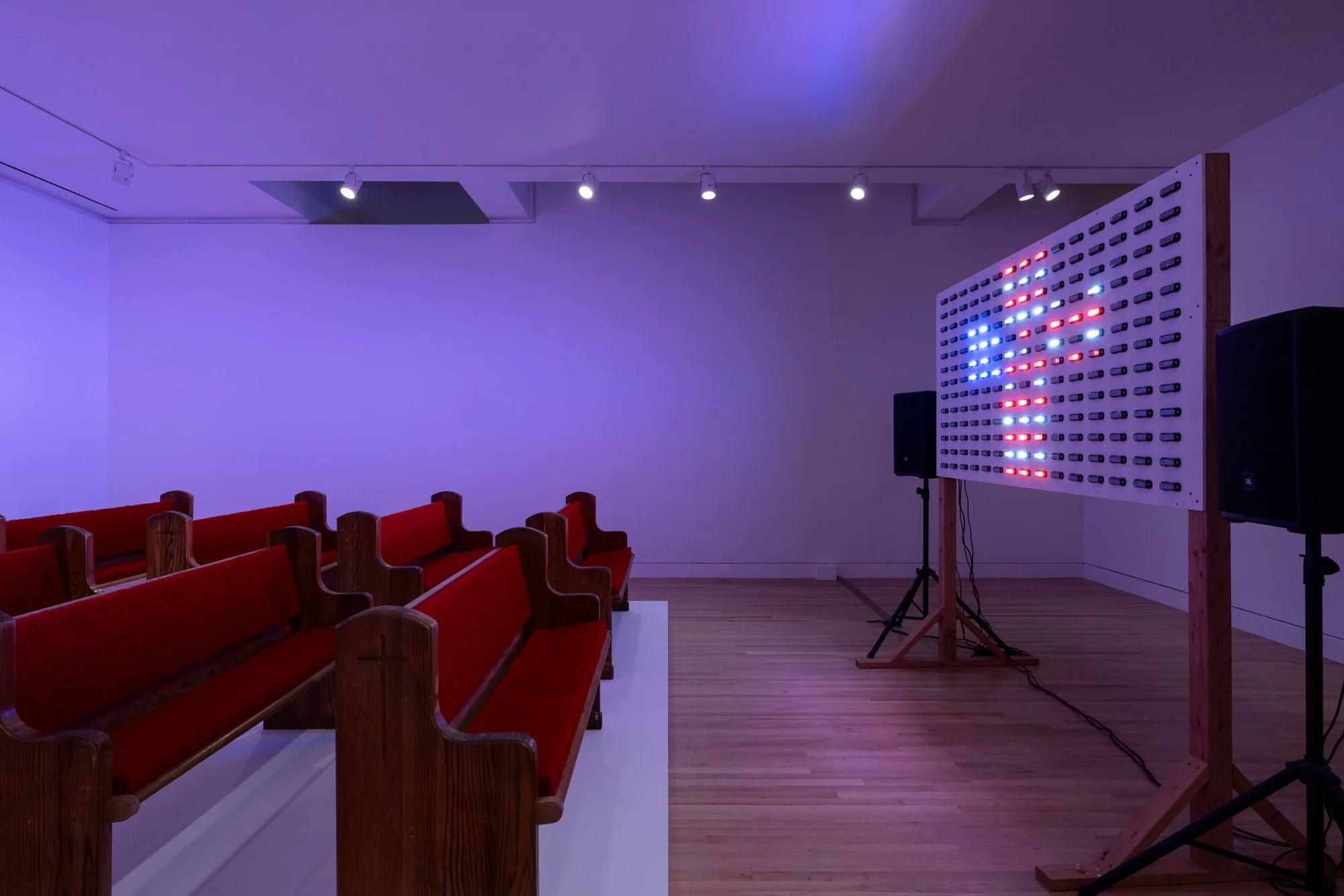 an LED panel showing a cross in front of church pews