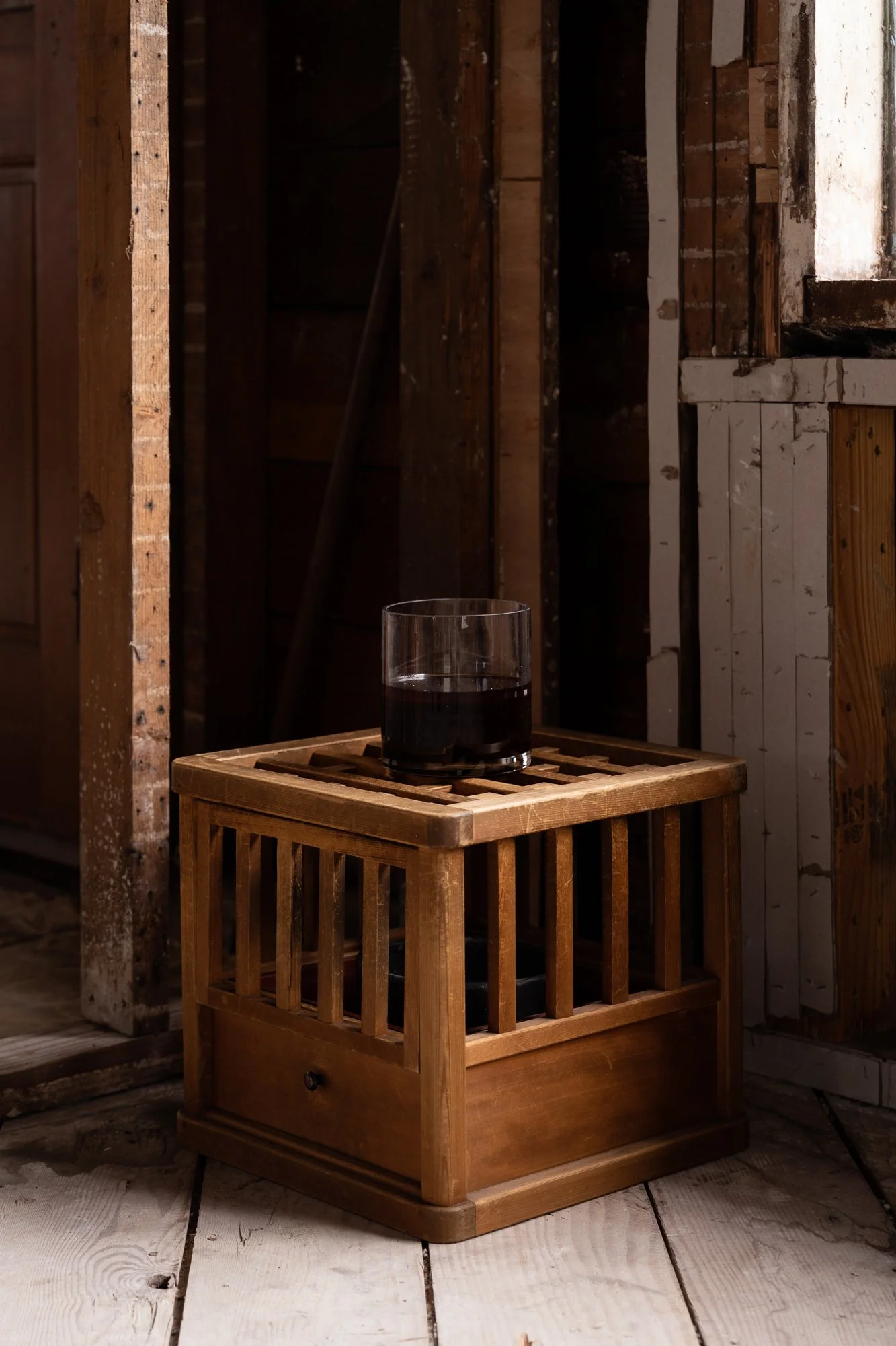 a glass vase with dark liquid sitting on a wooden box