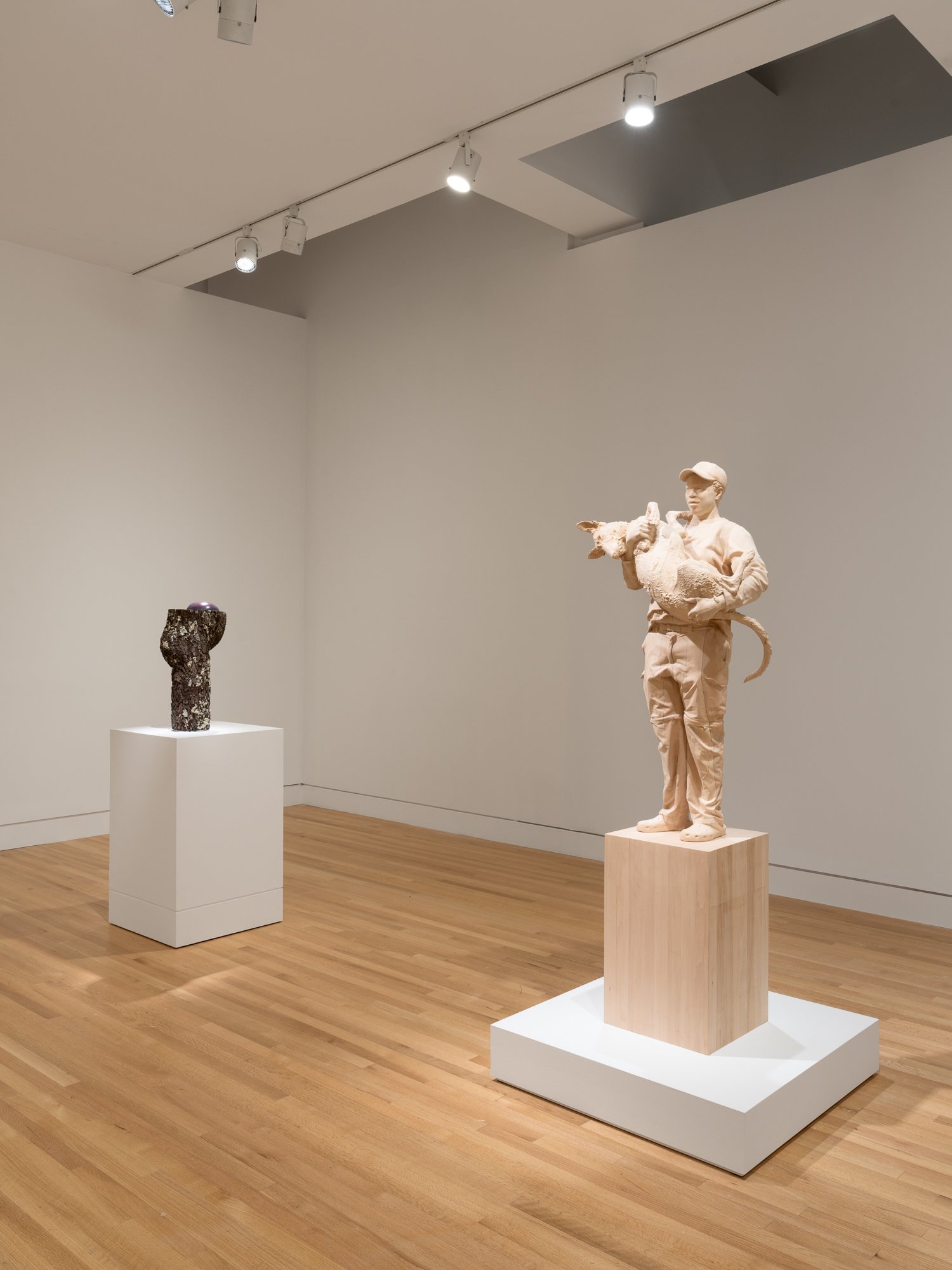 sculpture in the shape of tree trunk on the left; wooden sculpture of a figure holding a puppy on the right