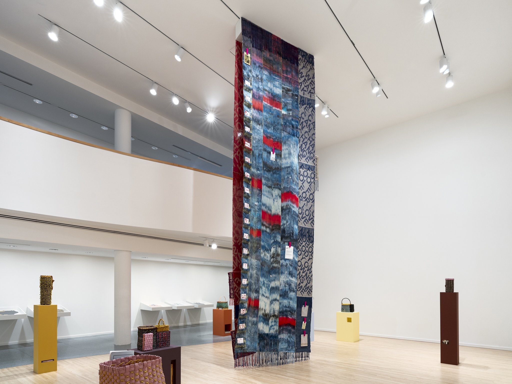 a large textile and various sculptures in a gallery