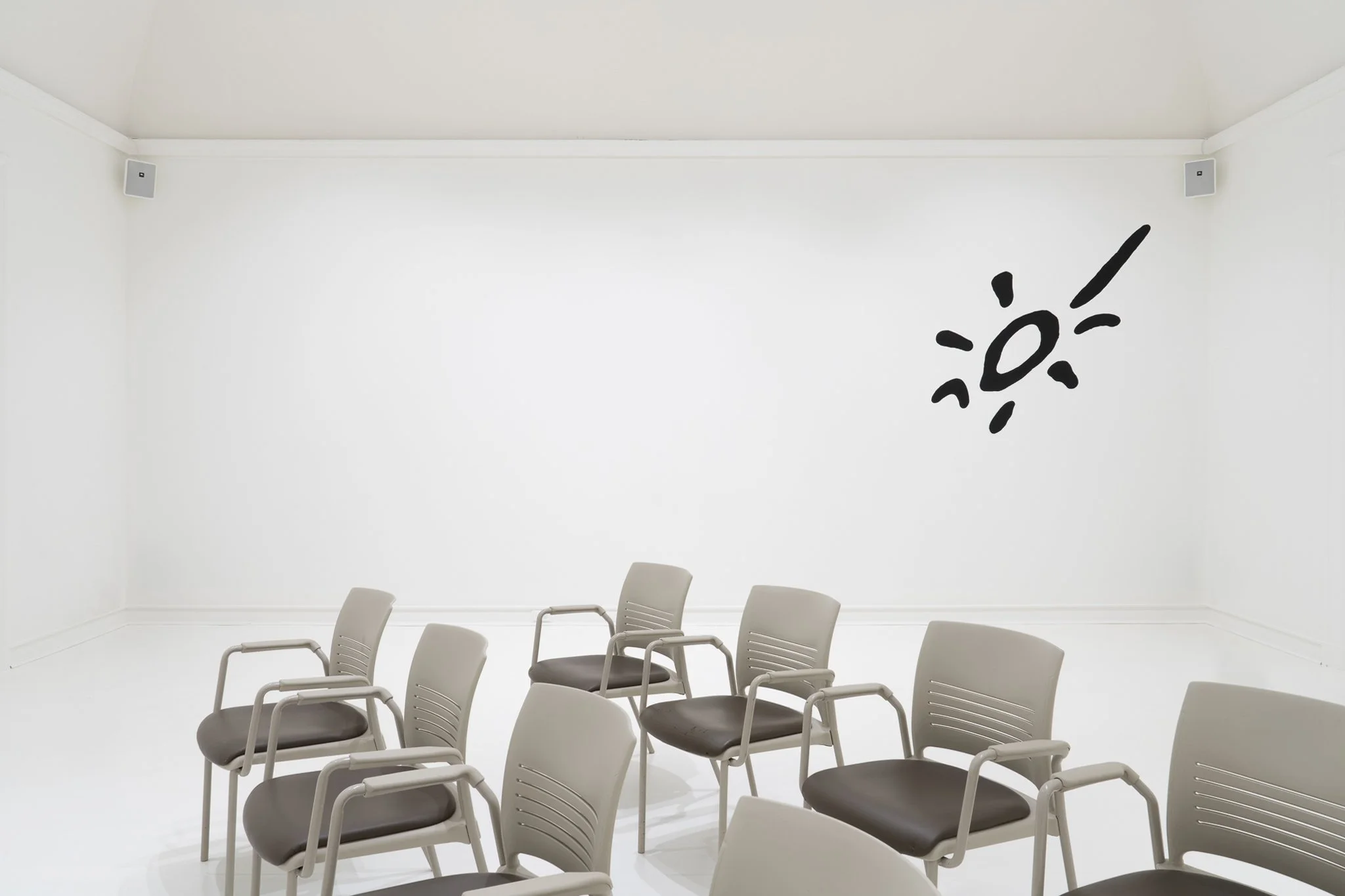 a white room with 8 chairs and a cartoon sun on the wall