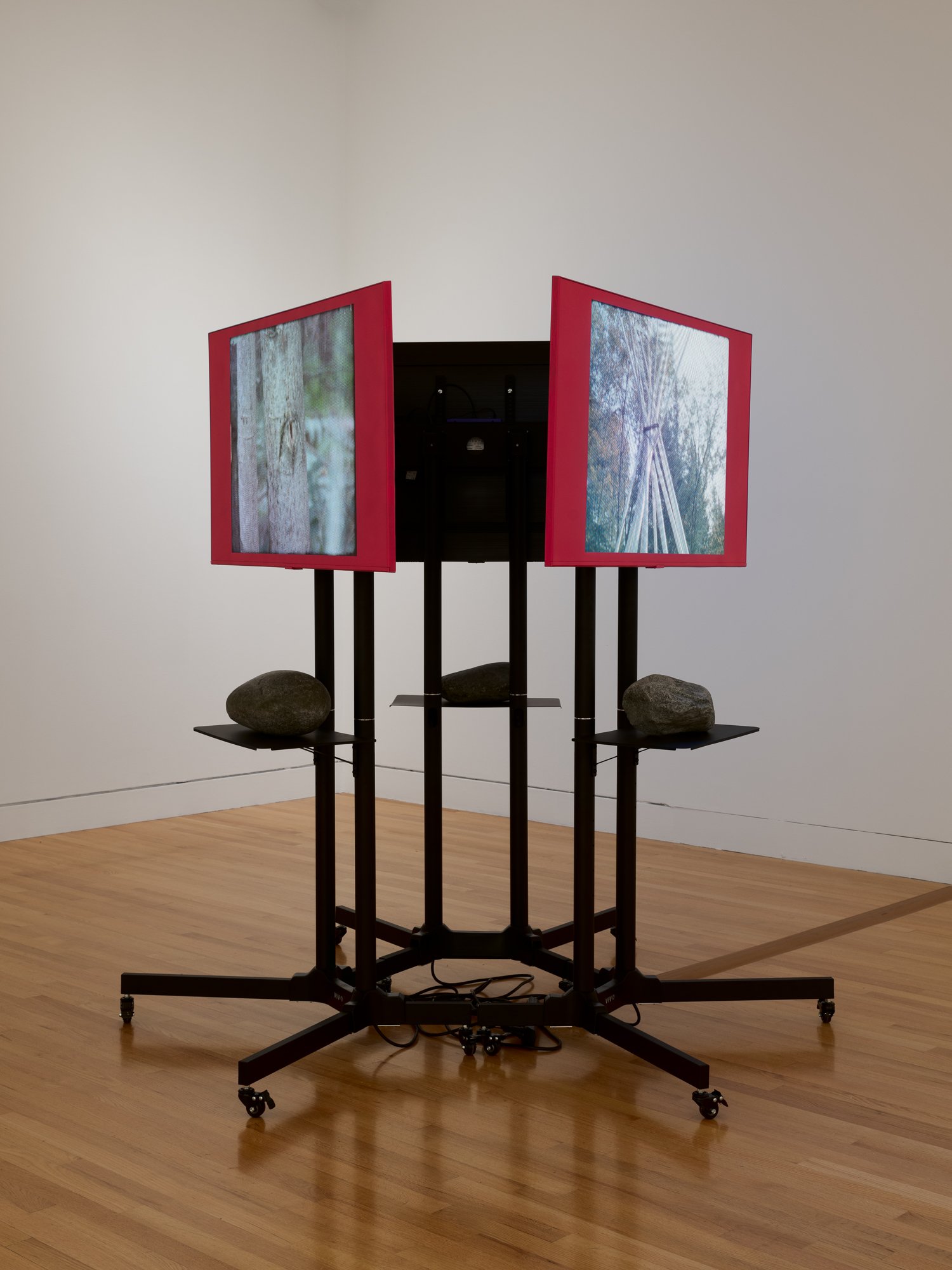 a video installation with 3 tv on stands and 3 large rocks