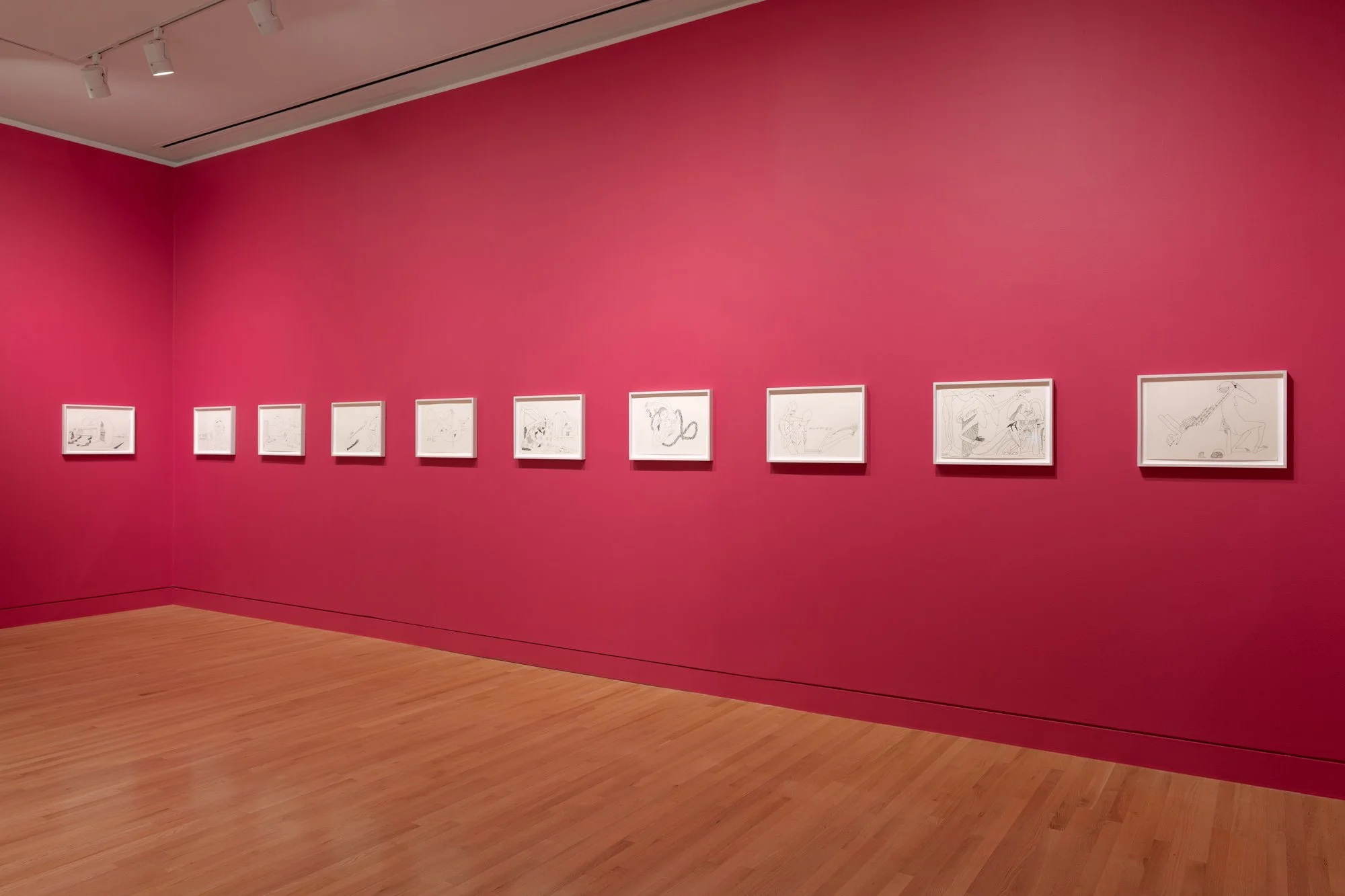 a series of drawings lined up on two red walls