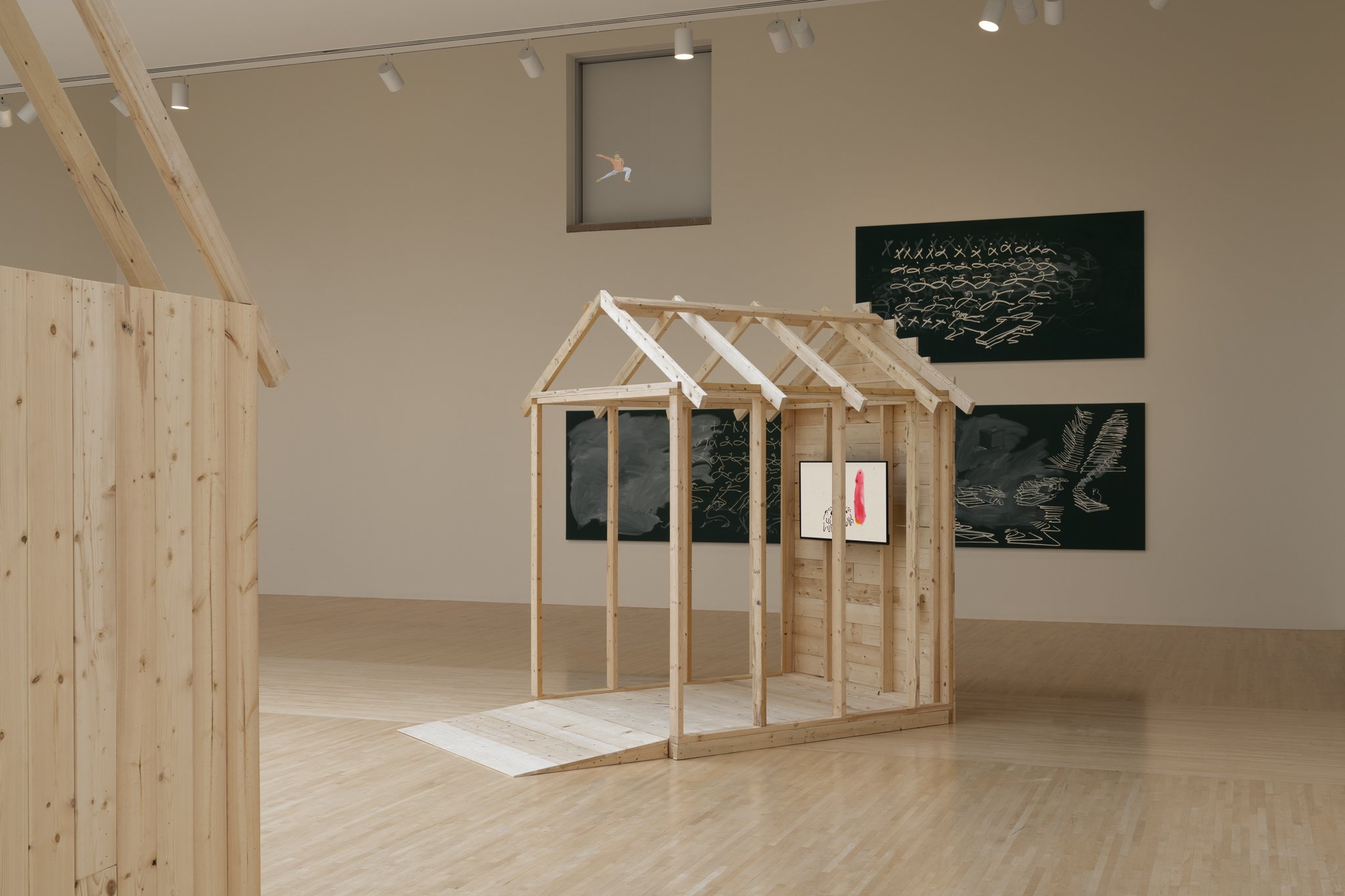 wood sheds with video screens and paintings in a gallery