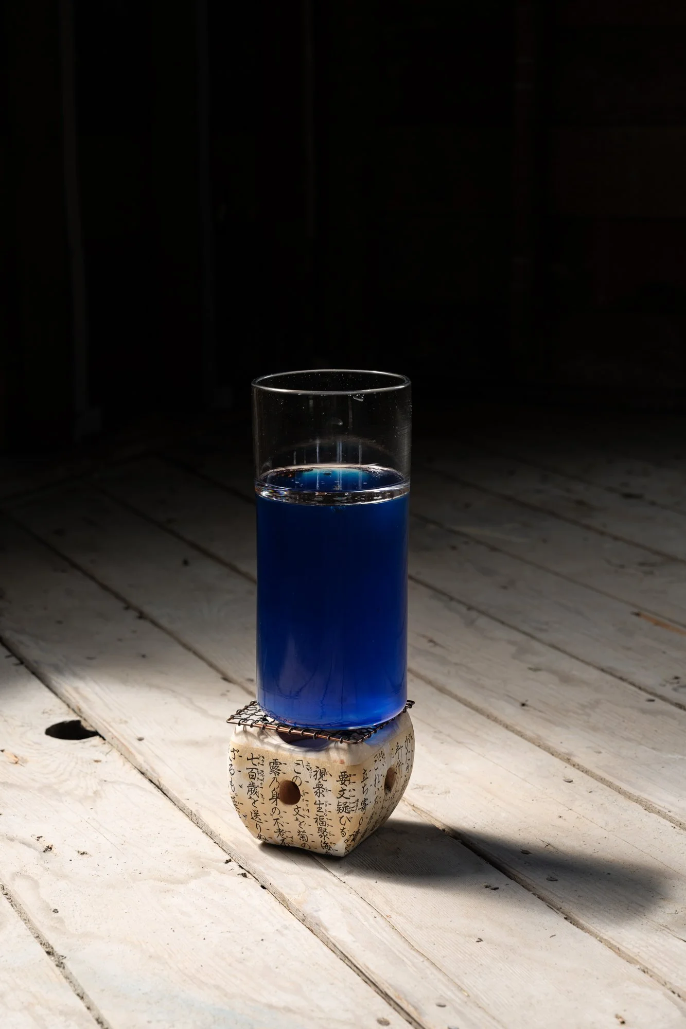 a glass vase with blue liquid sits on a mini grill