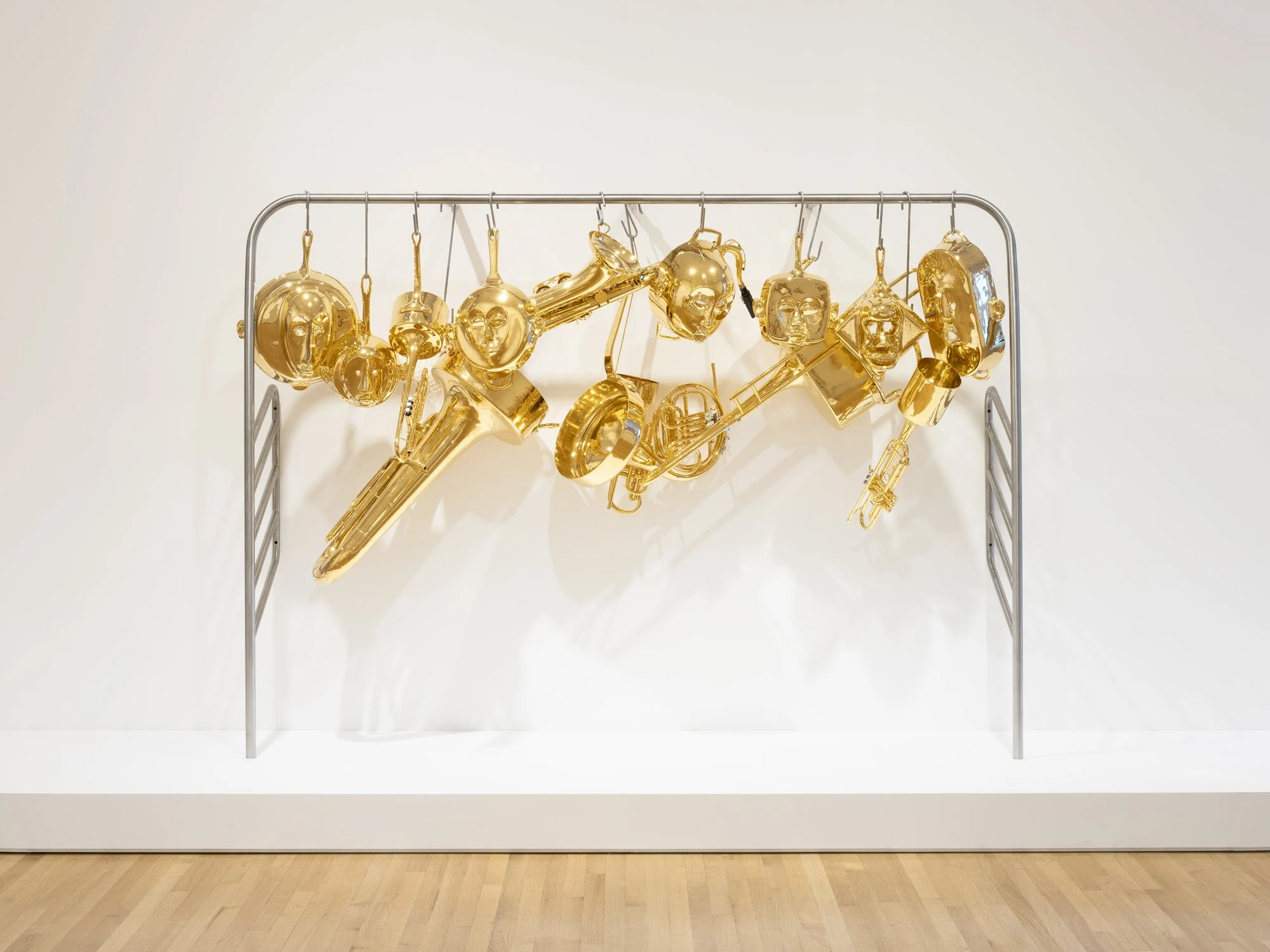 brass pans and pots in the shapes of masks hung on a rack