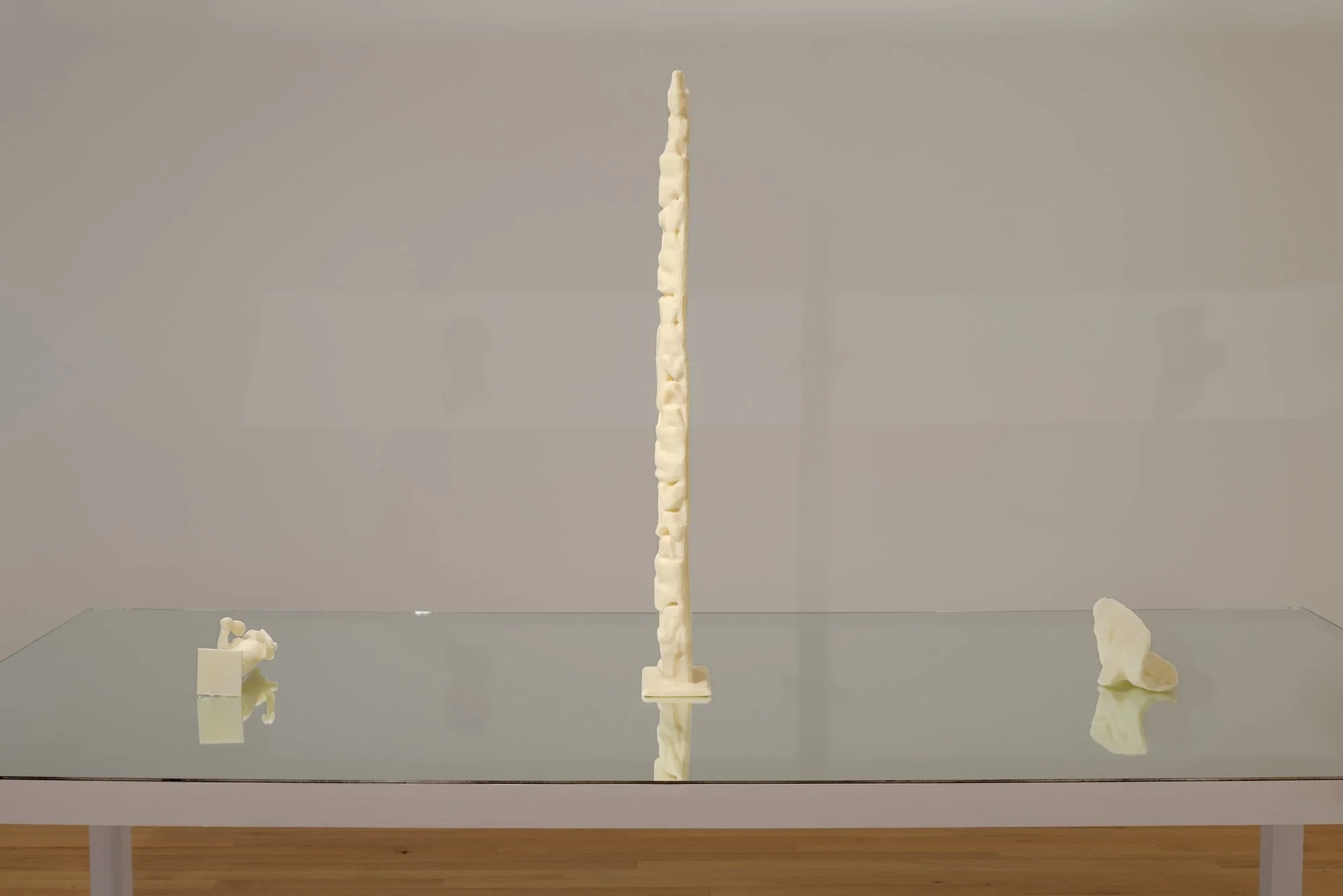 three 3D printed sculptures on a table with a mirror top