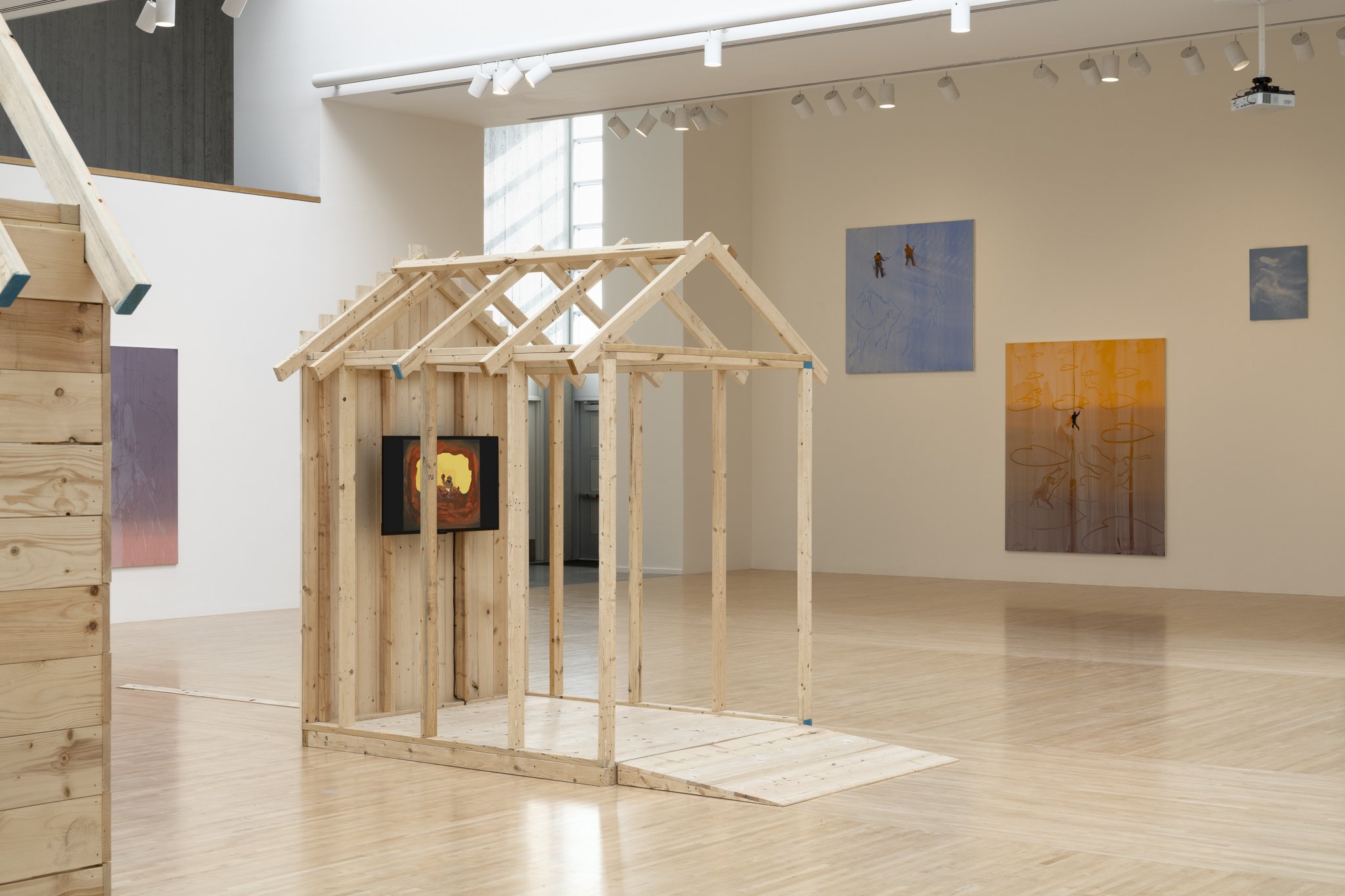 wood sheds with video screens and paintings in a gallery