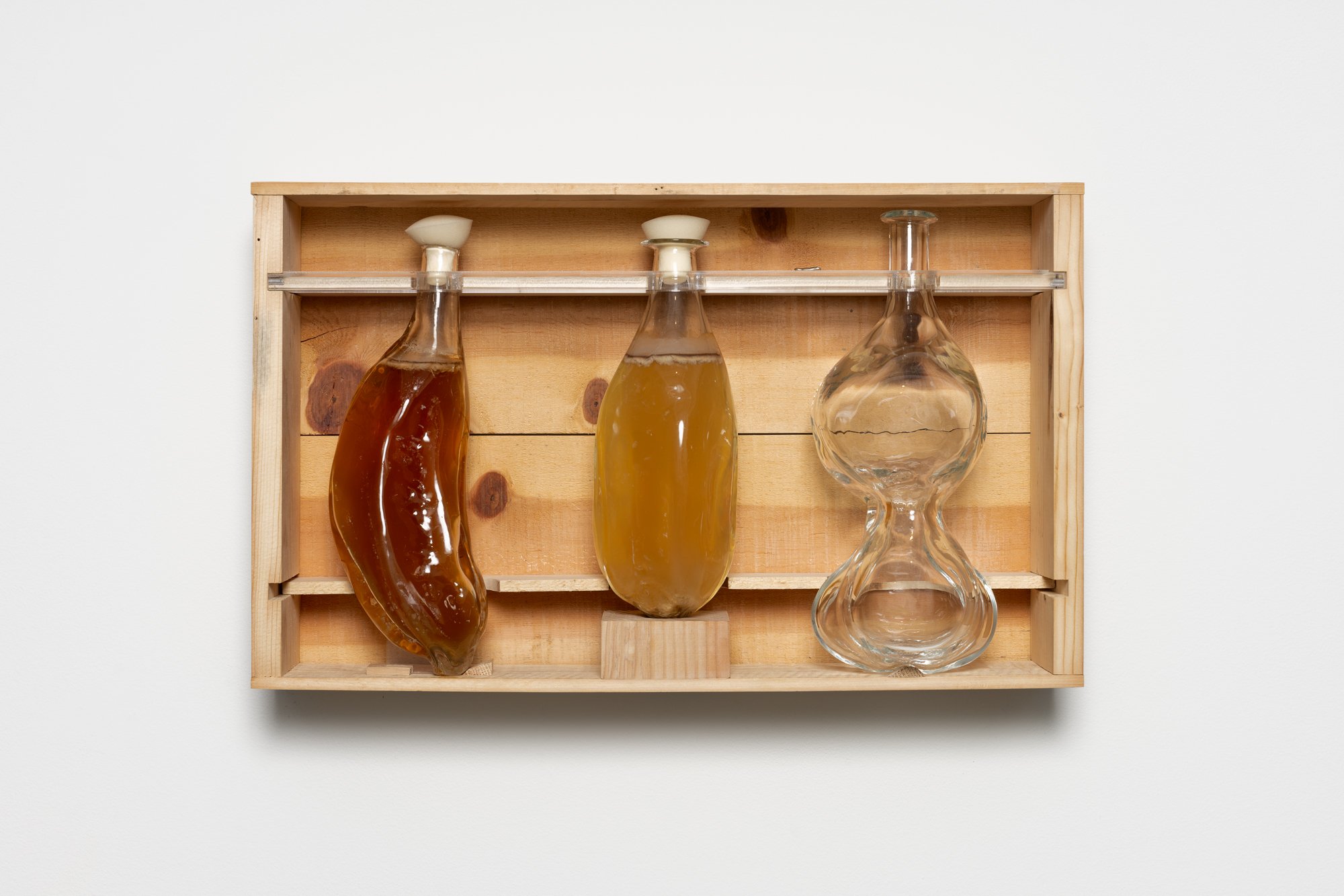 three glass vessels with liquids in a wooden box