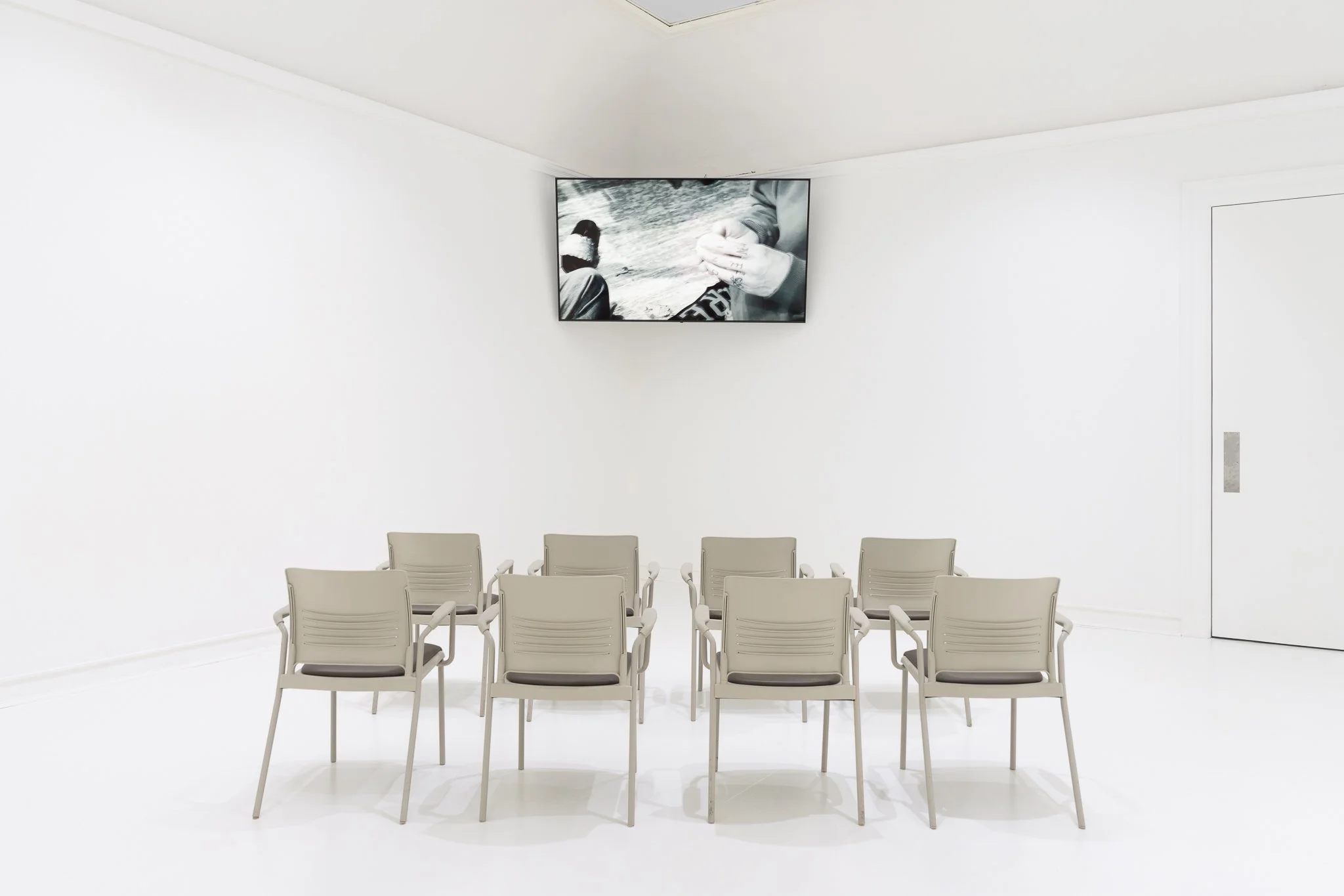 a tv and 8 chairs in a white room