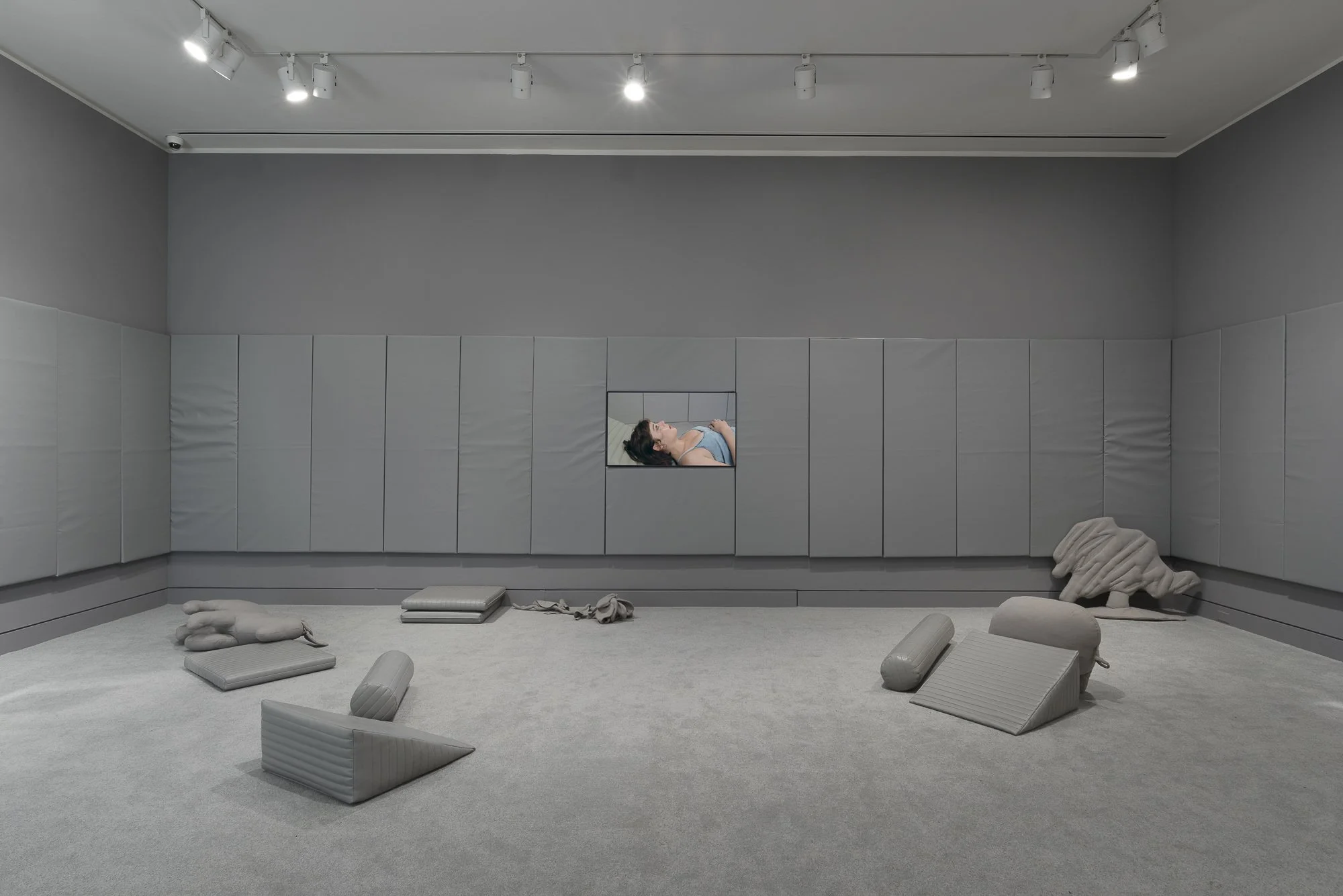 gray room with soft sculptures and a video
