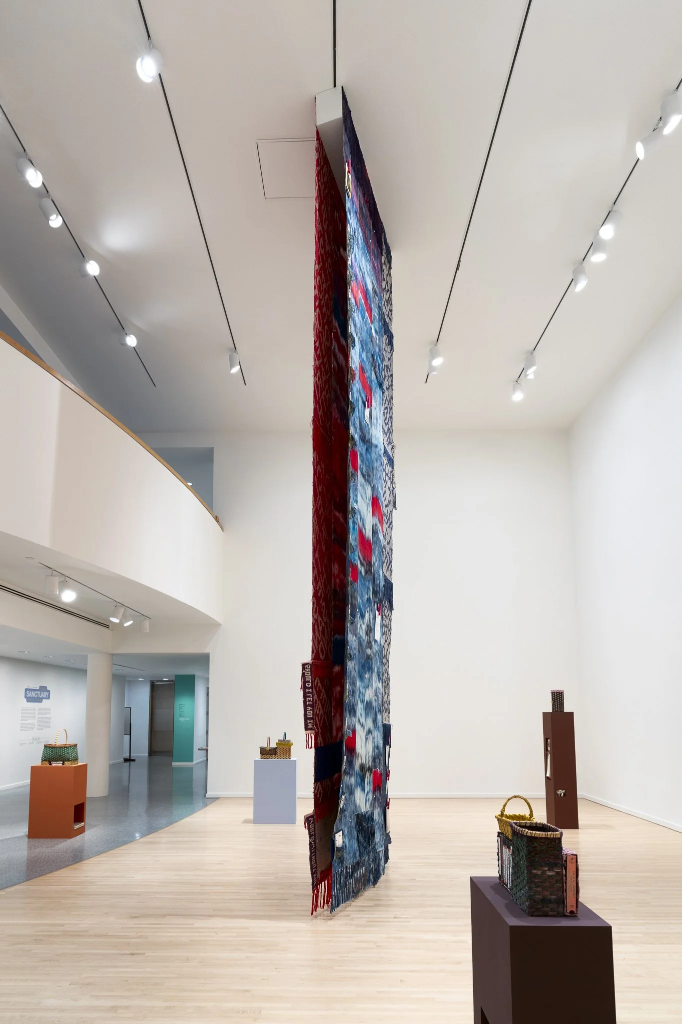 a large textile and various sculptures in a gallery