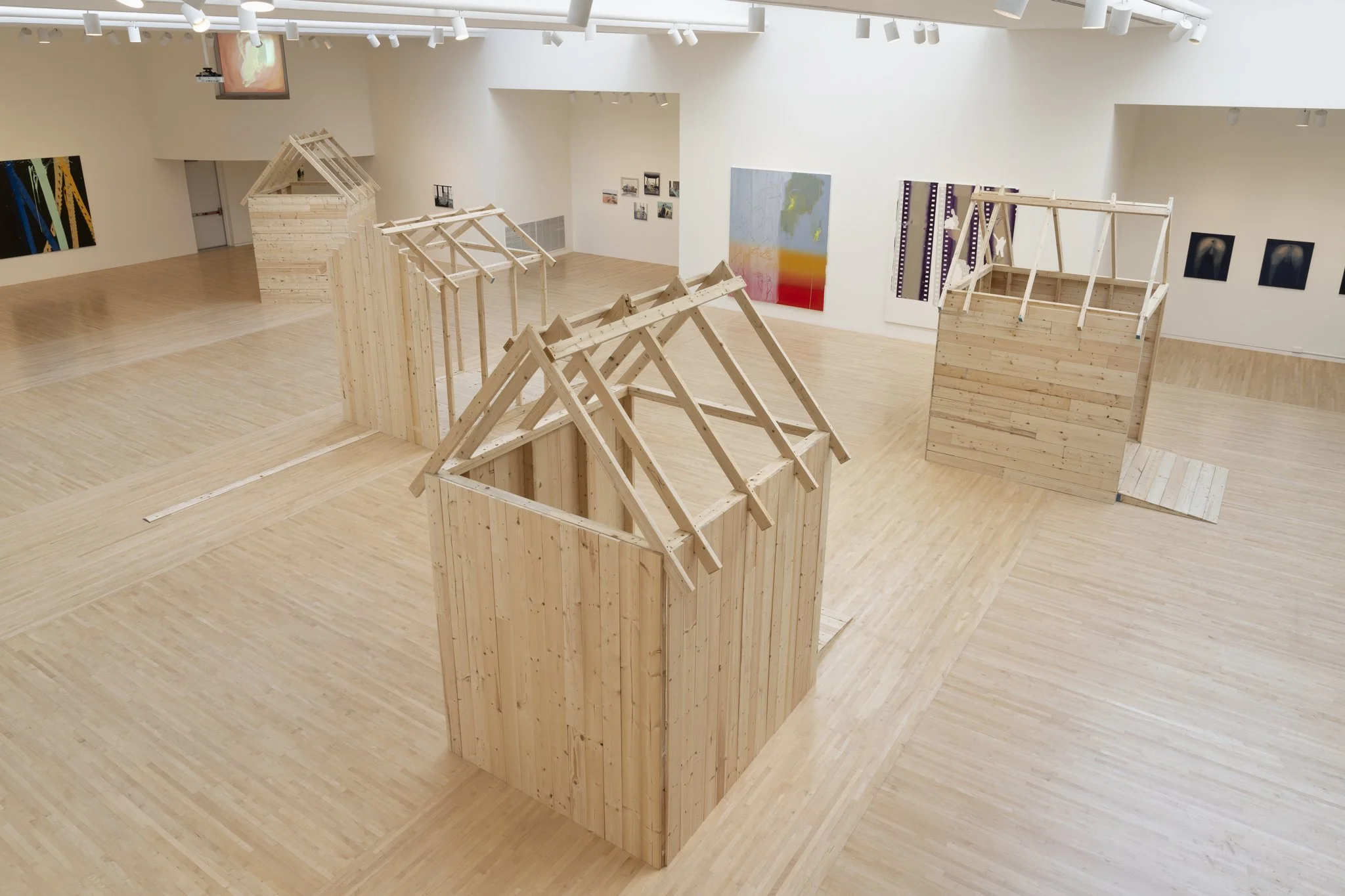 wood sheds with video screens and paintings in a gallery