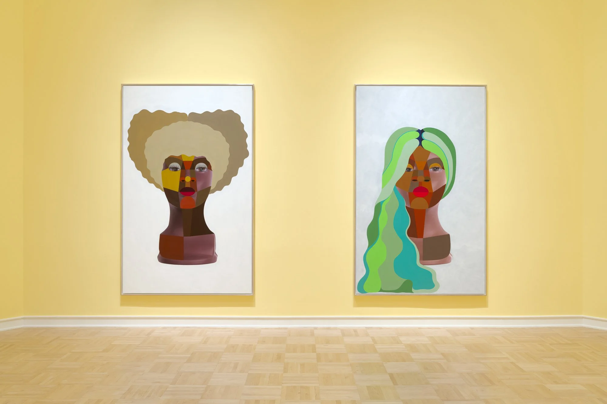 two paintings of heads on a yellow wall