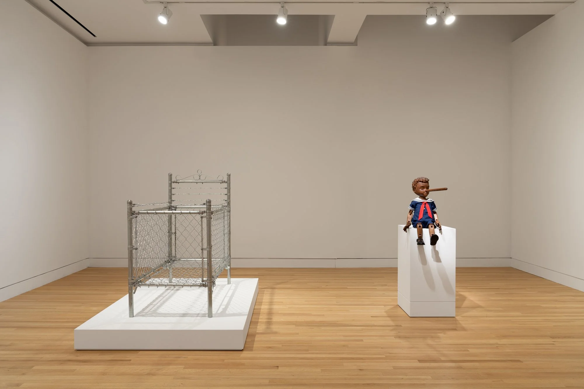 a barbed wire nursery bed on the left; a wooden pinocchio doll on the right