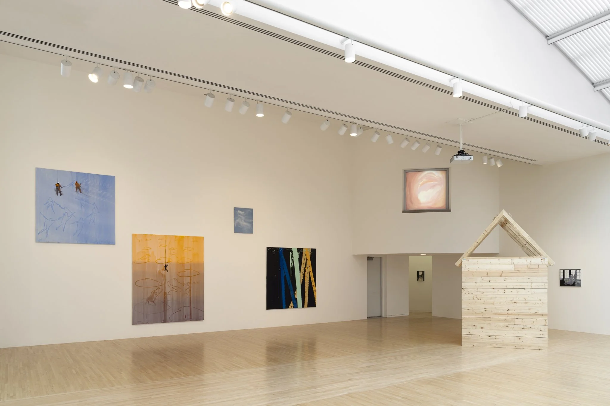 wood sheds with video screens and paintings in a gallery