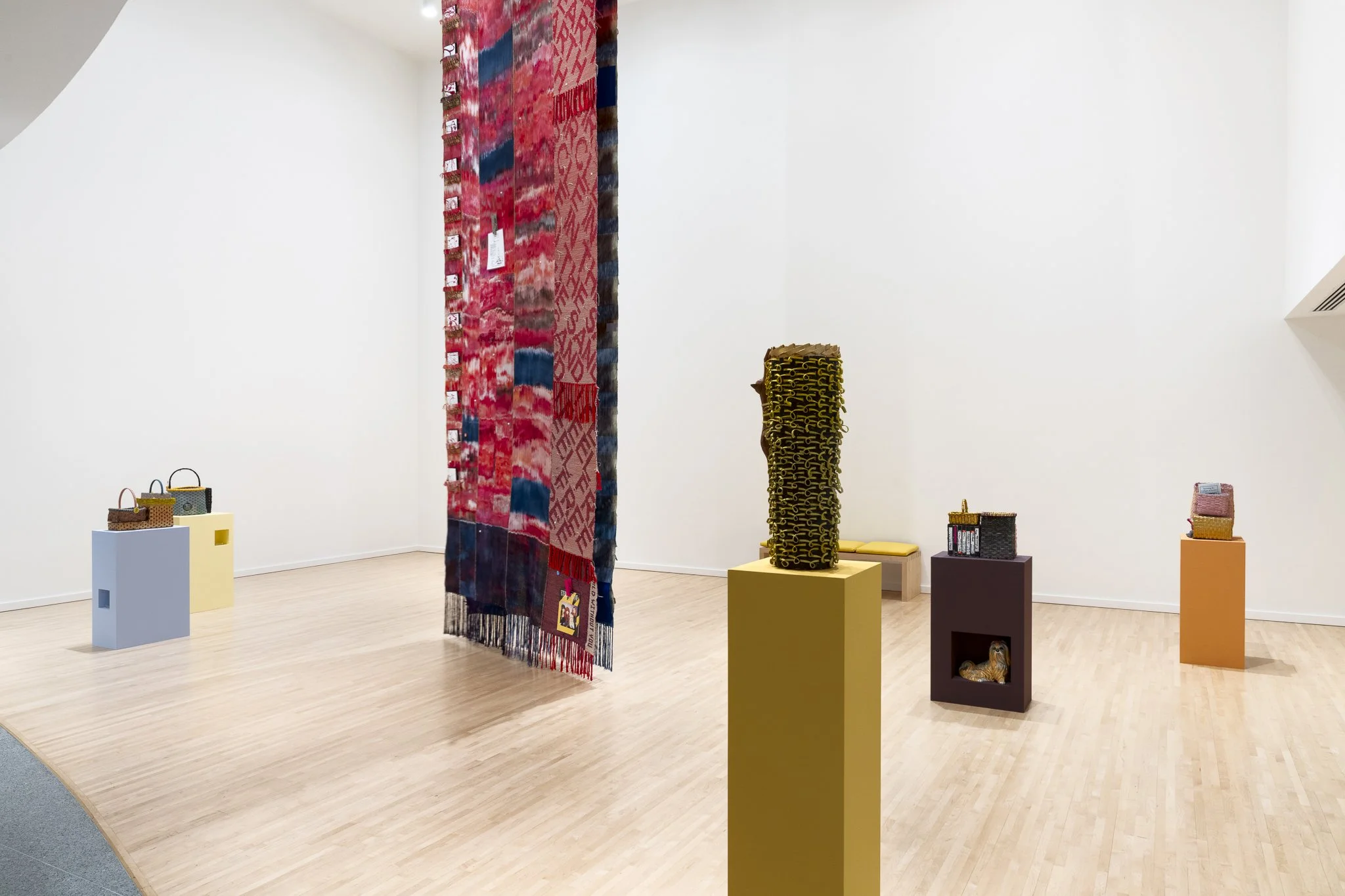 a large textile and various sculptures in a gallery