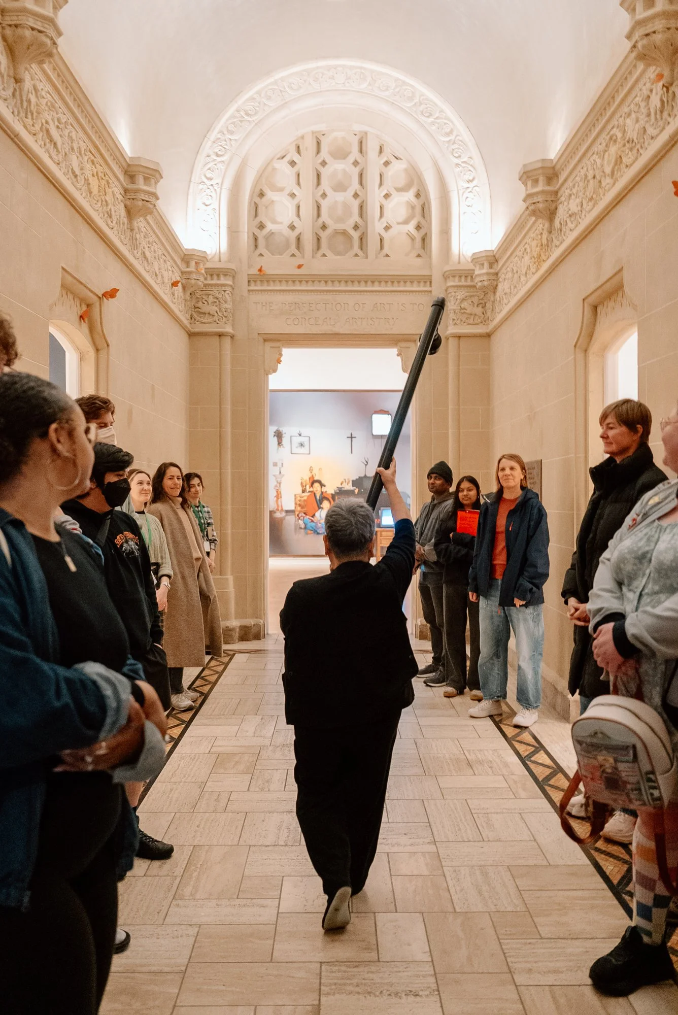 a performer holding a large pipe walking through a crowd