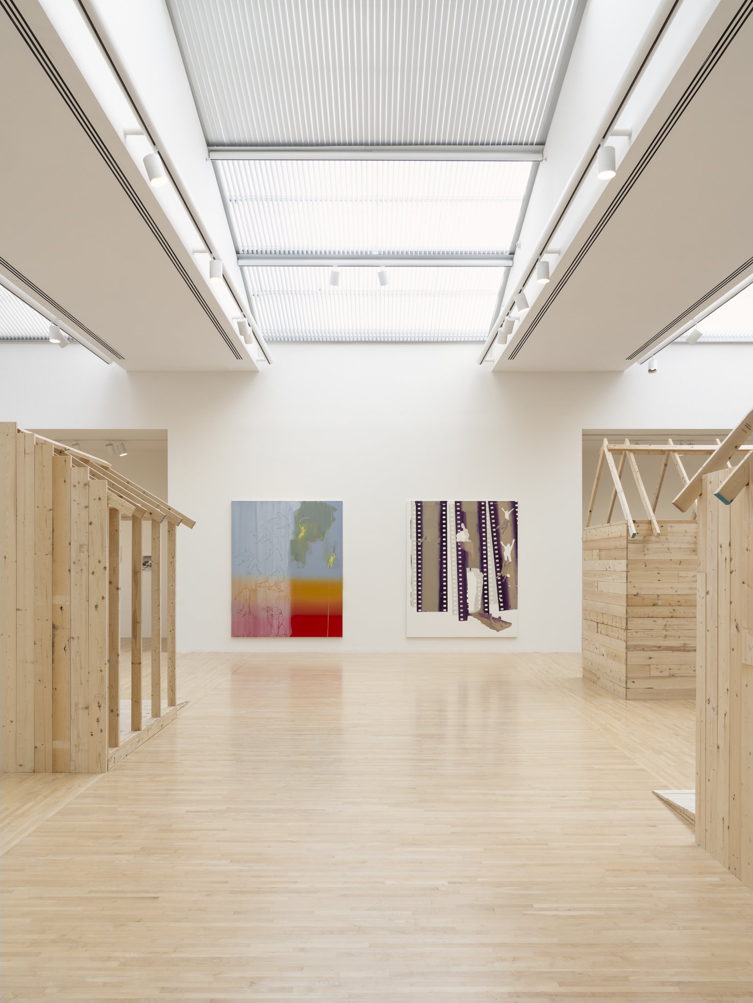 wood sheds with video screens and paintings in a gallery