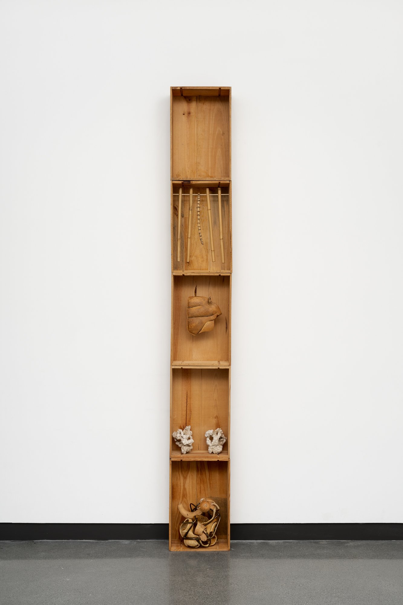 5 wooden boxes stacked on top of each other, with sculptures inside.