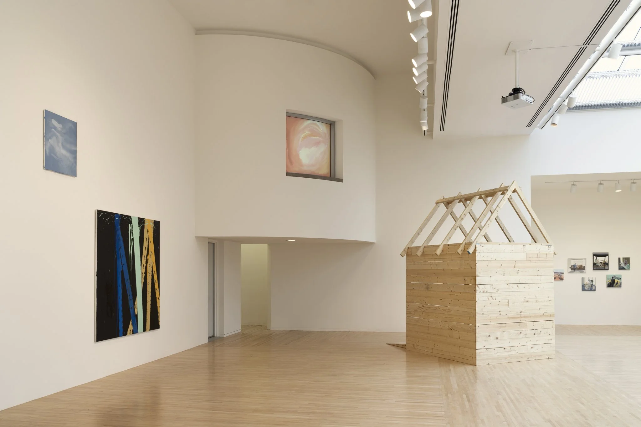 wood sheds with video screens and paintings in a gallery