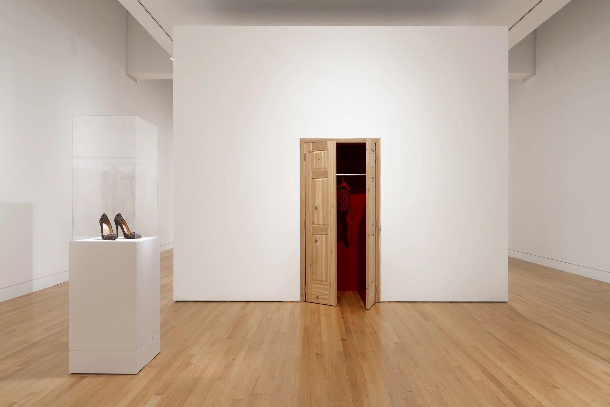 a pair of heels on a podium; an open door revealing red skeletons.