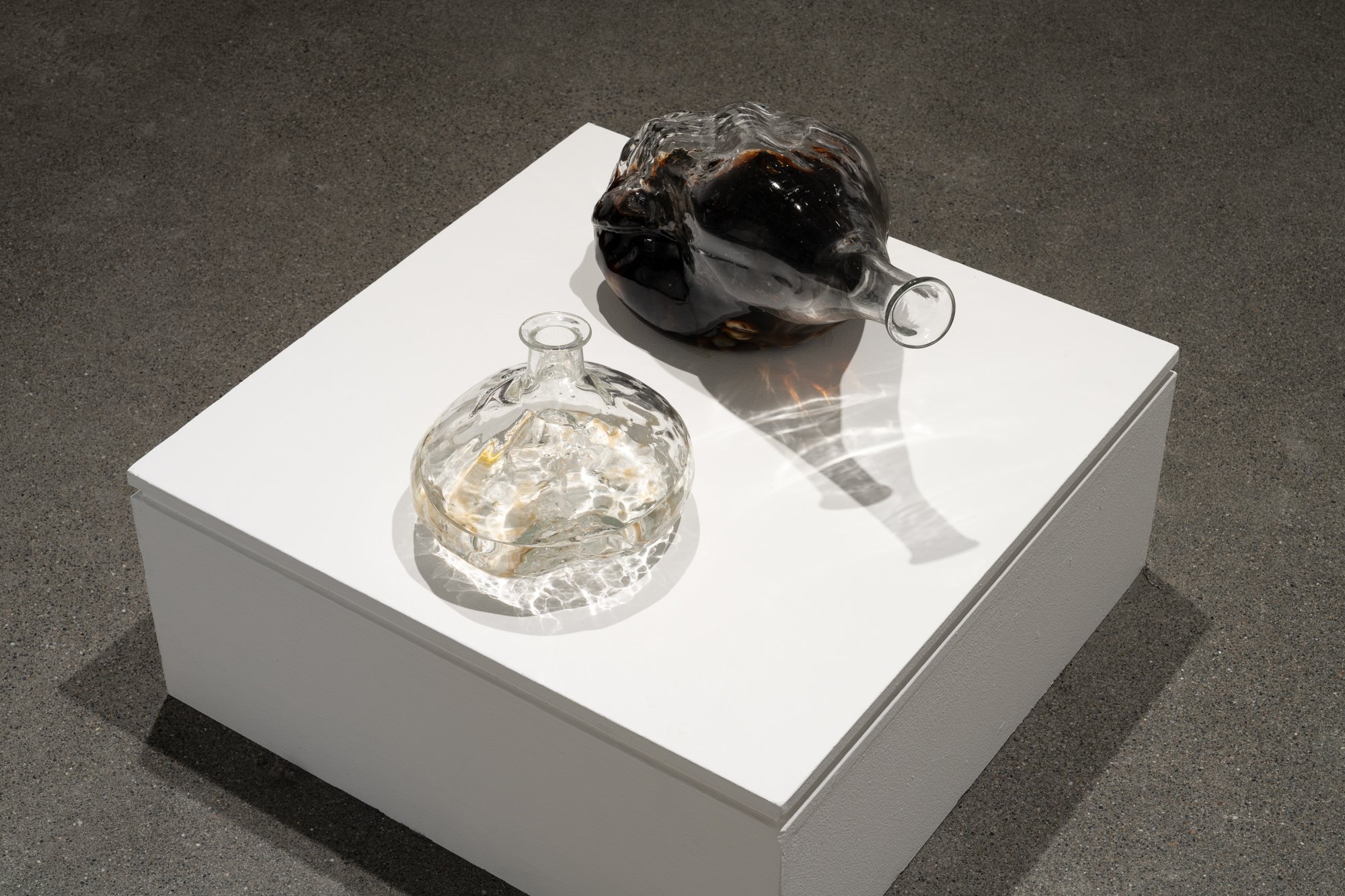 two glass vessels with liquid on a podium