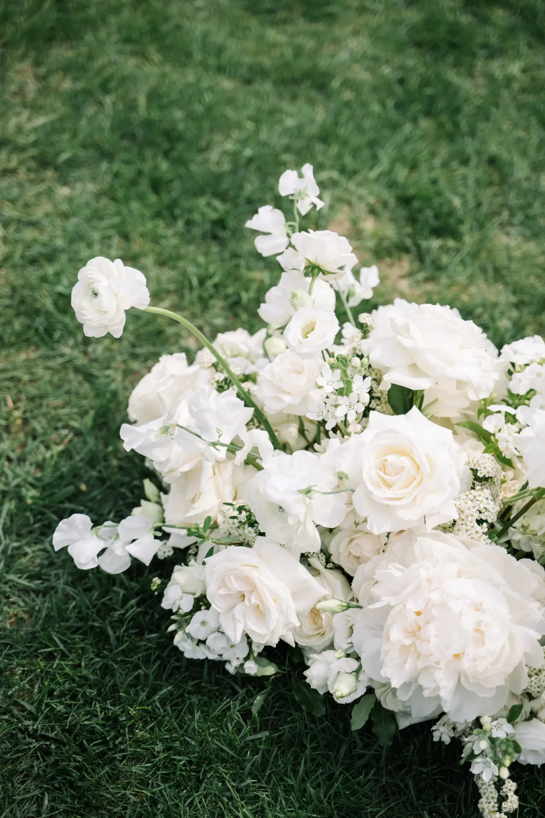 A bouquet of white flowers resting on green grass.