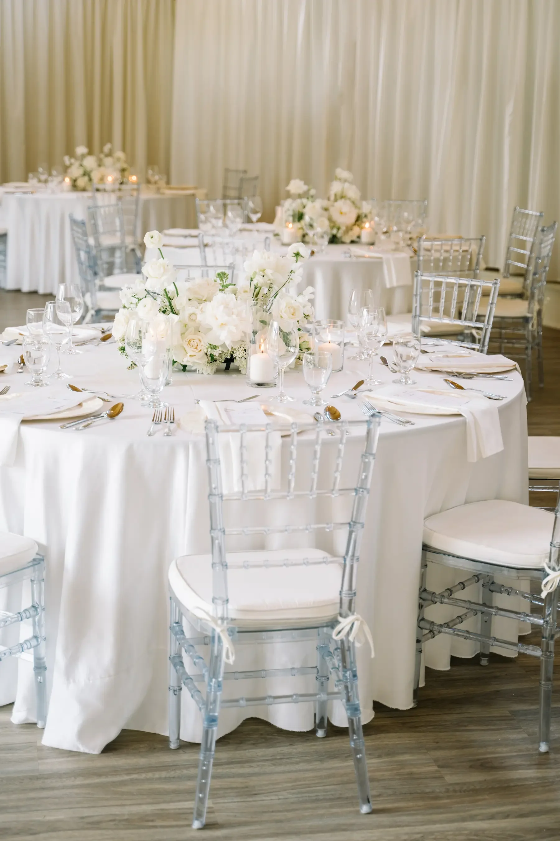Elegant event table decorated with white flowers, candles, and fine glassware, set for a formal gathering or wedding reception.