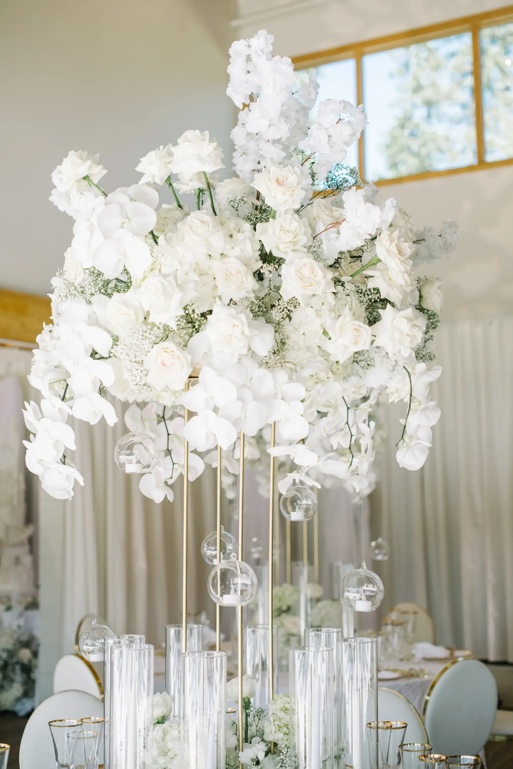 Elegant white floral centerpiece with candles in a decorated event setting.