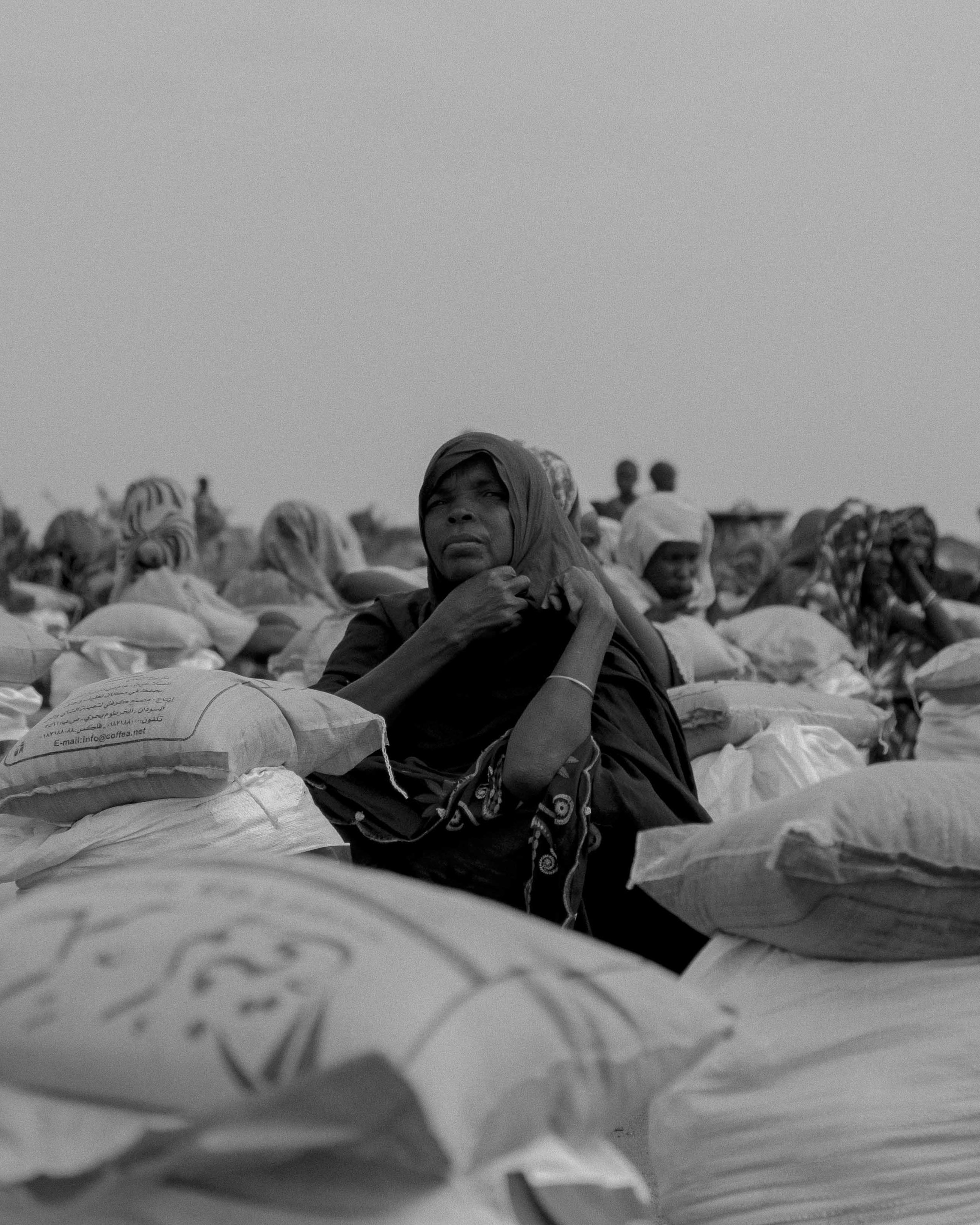 Women, displaced from war, wait to be able to leave with their food parcels in the El Serif refugee camps.