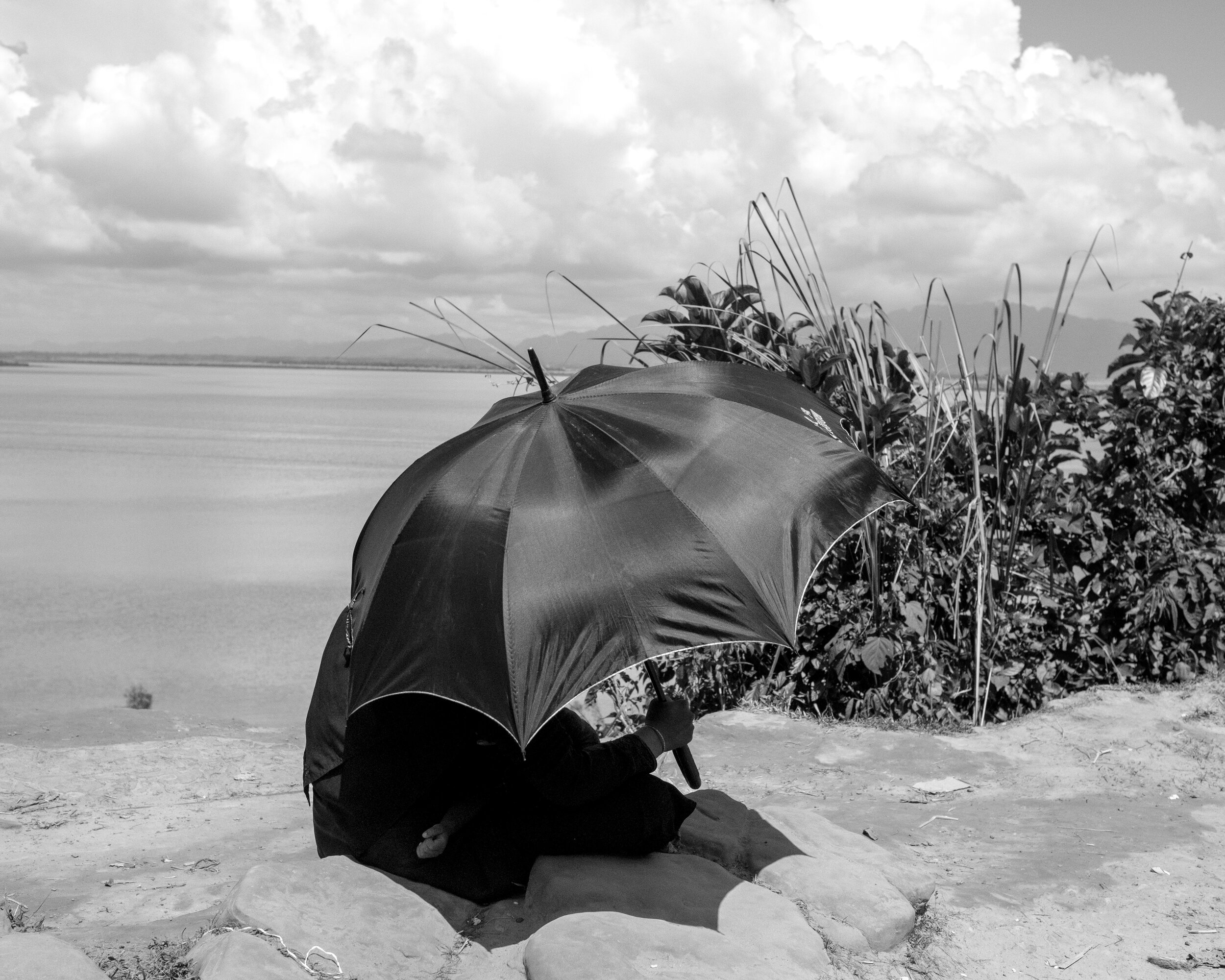  In Teknaf, a Rohingya woman and her baby in front of the Naf River, which marks the border between Myanmar and Bangladesh, protect themselves from the sun with an umbrella. 